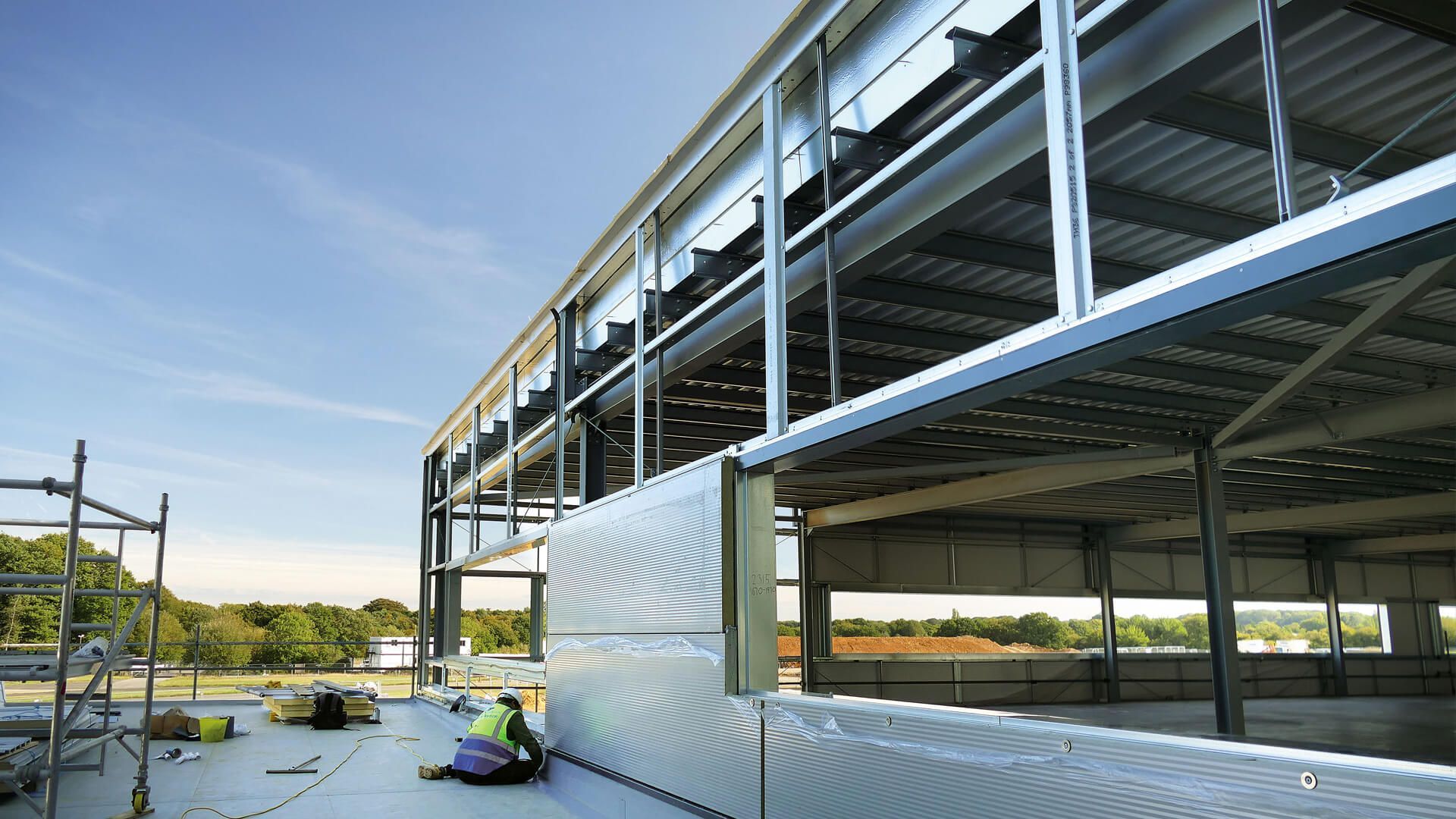 A man is laying on the roof of a building under construction.