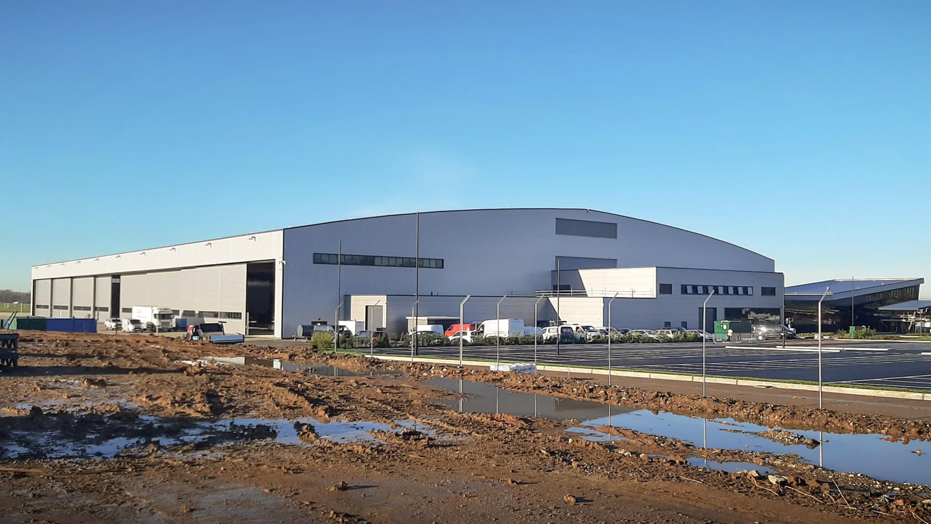 A large white aircraft hangar with a blue sky in the background