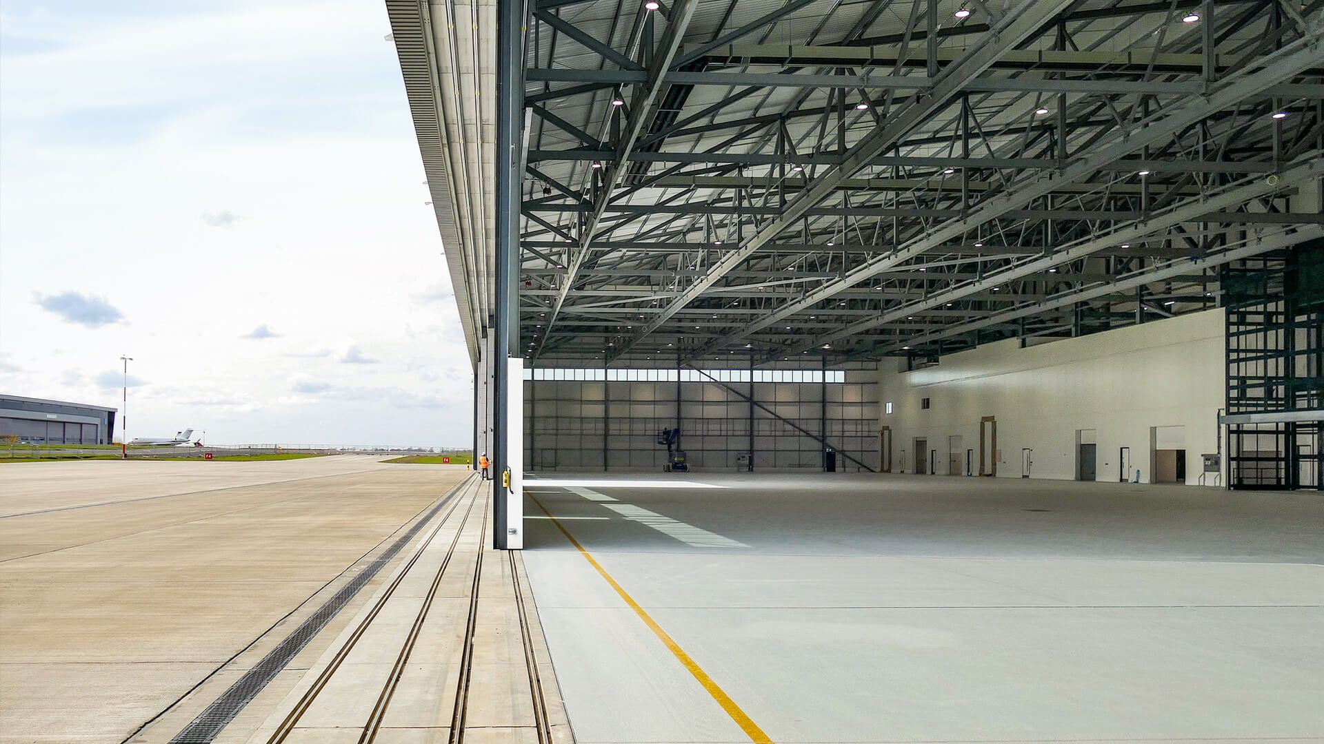 A large empty hangar with a runway in the background.
