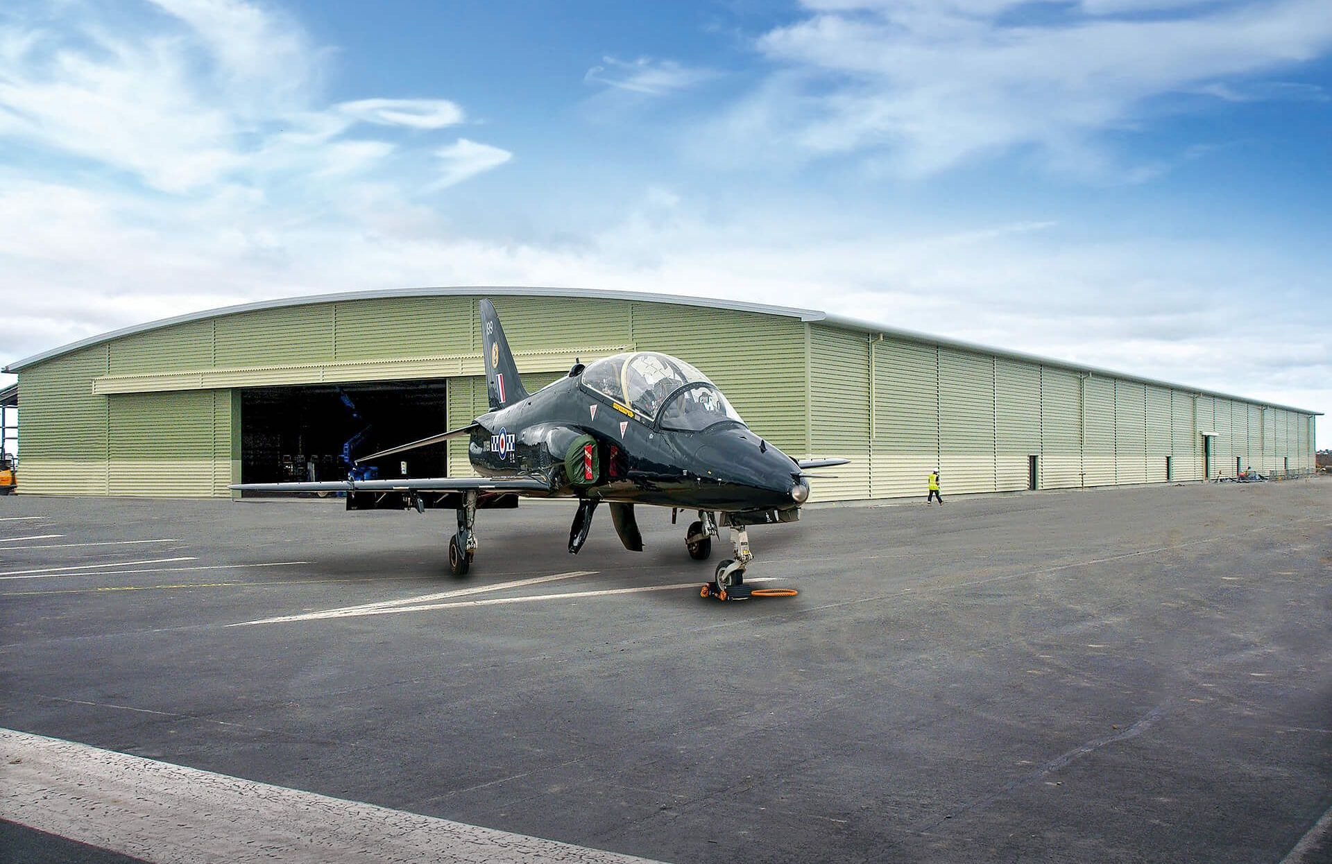 A fighter jet is parked in front of a hangar.