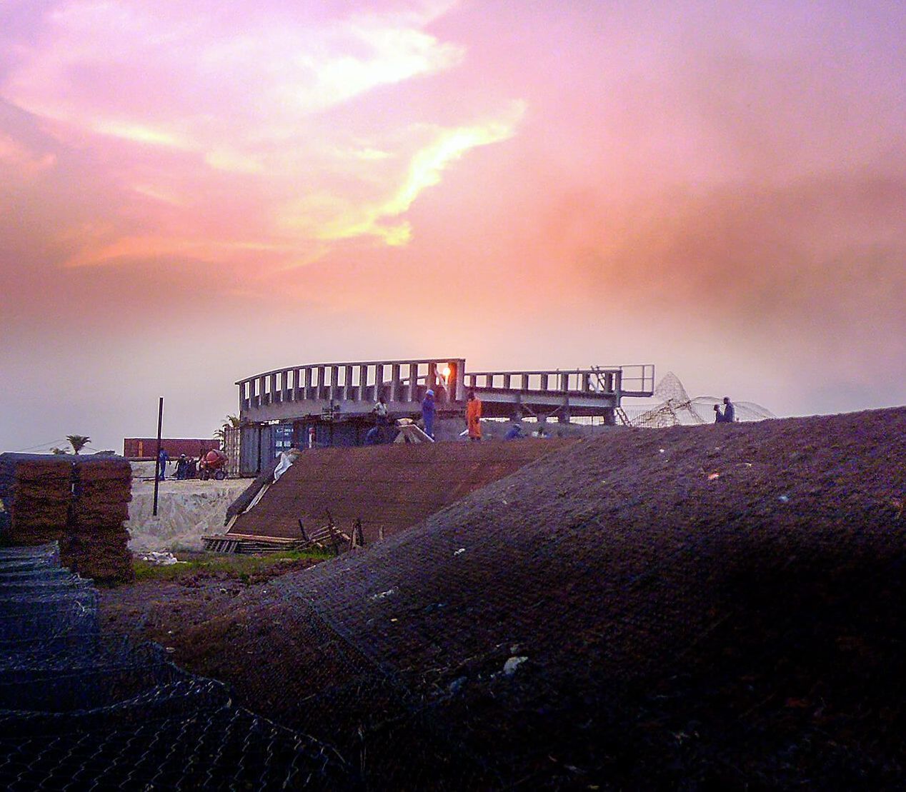 A group of people standing on top of a hill with a sunset in the background