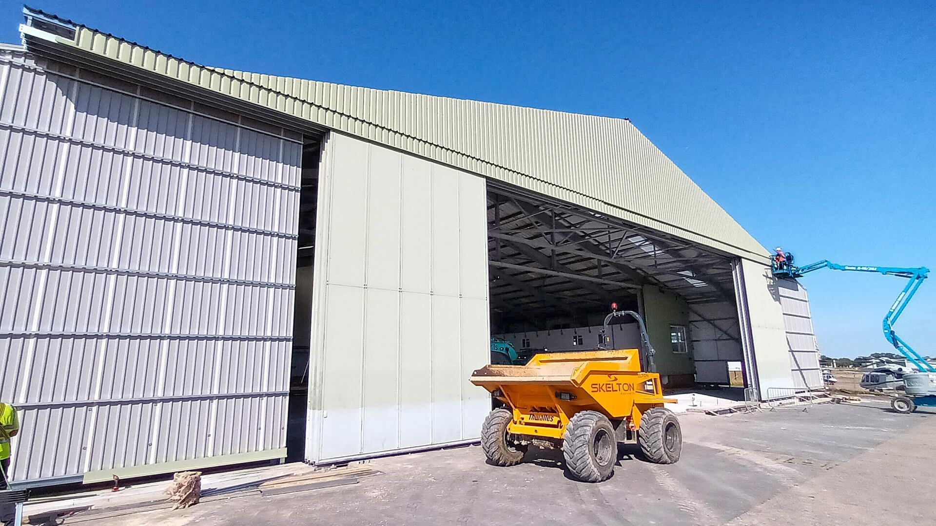 A yellow dump truck is parked in front of a large building.