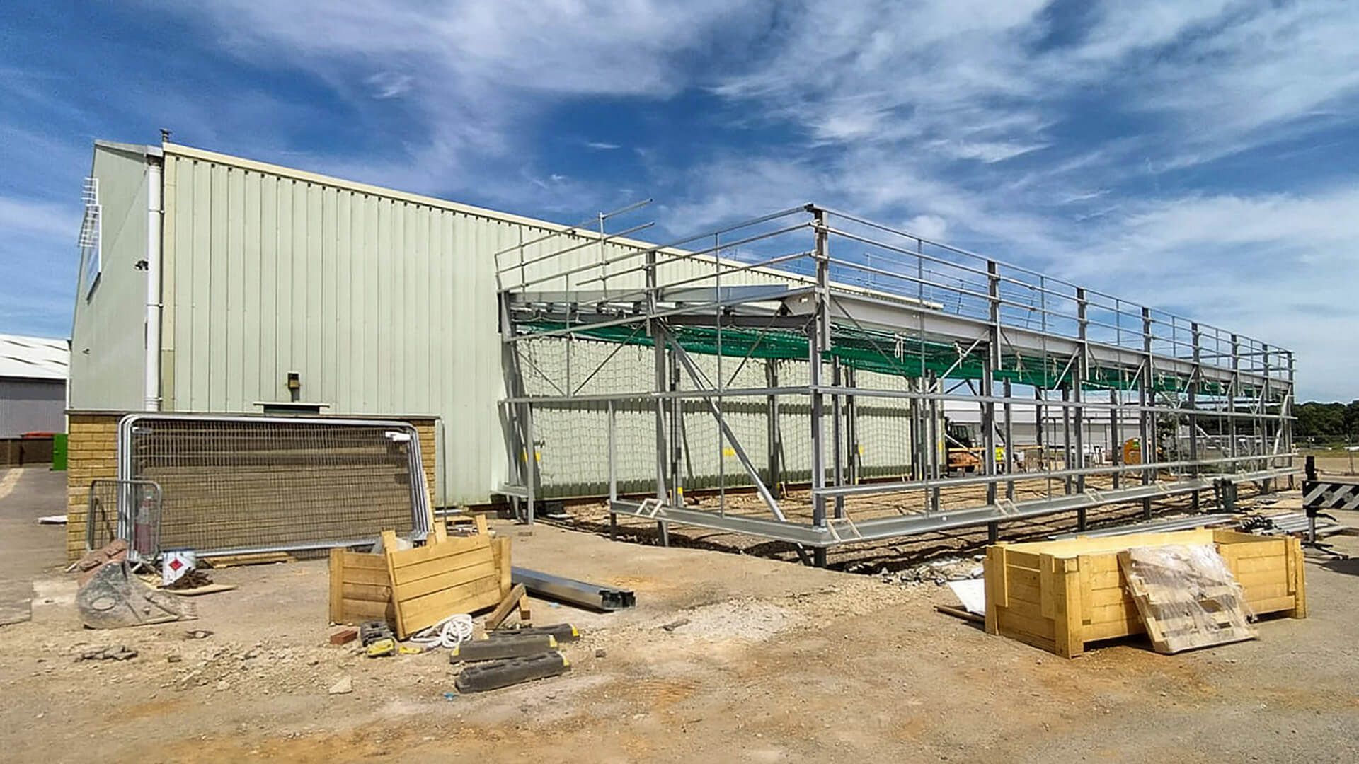 A large building is being built in the middle of a dirt field.