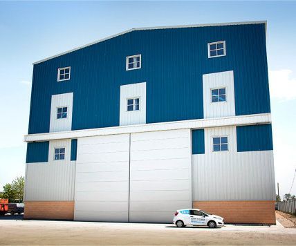 A blue and white building with a white car parked in front of it.