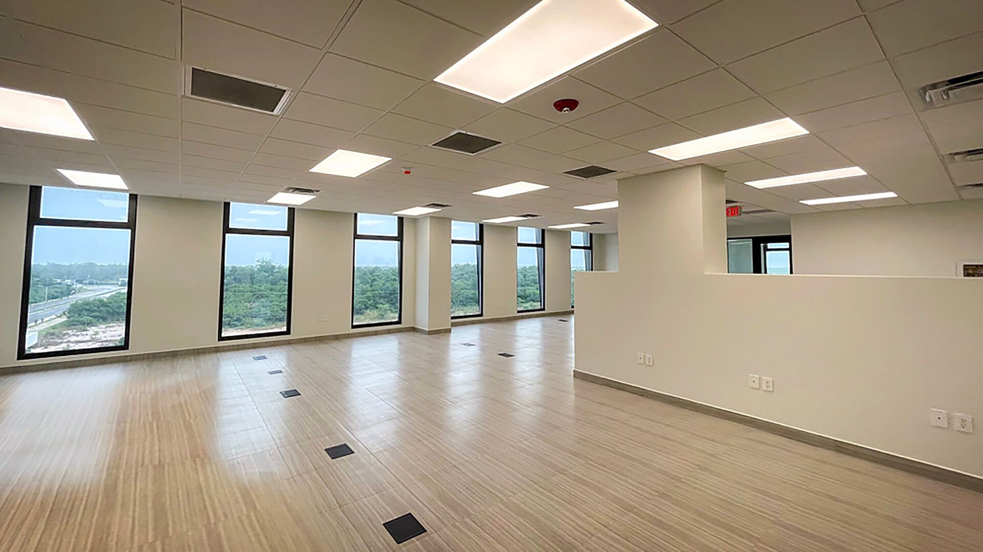 A large empty room with a lot of windows and ceiling lights.