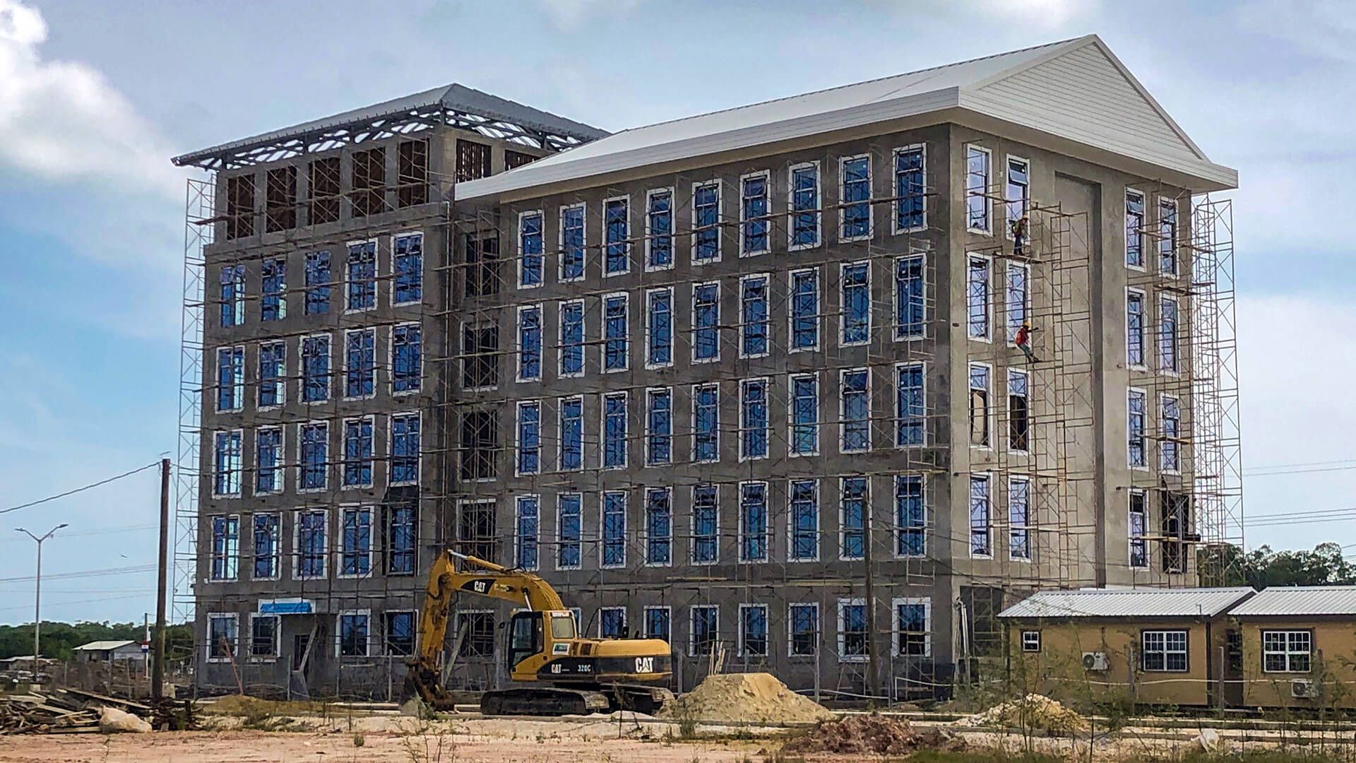A large building under construction with a bulldozer in front of it.