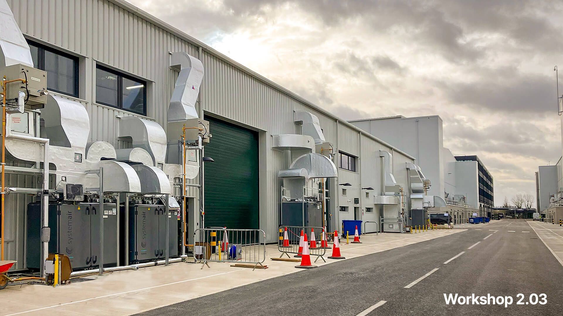 A large industrial building with a green door is being built.