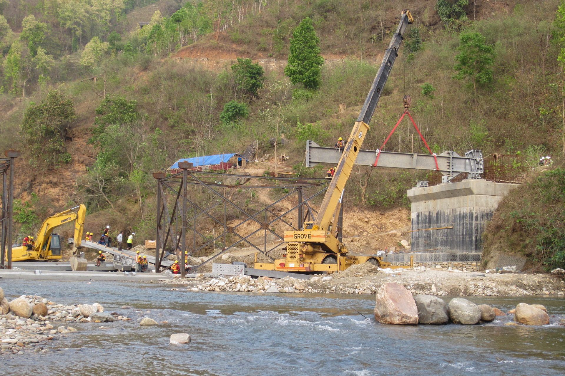 A yellow crane is lifting a bridge over a river