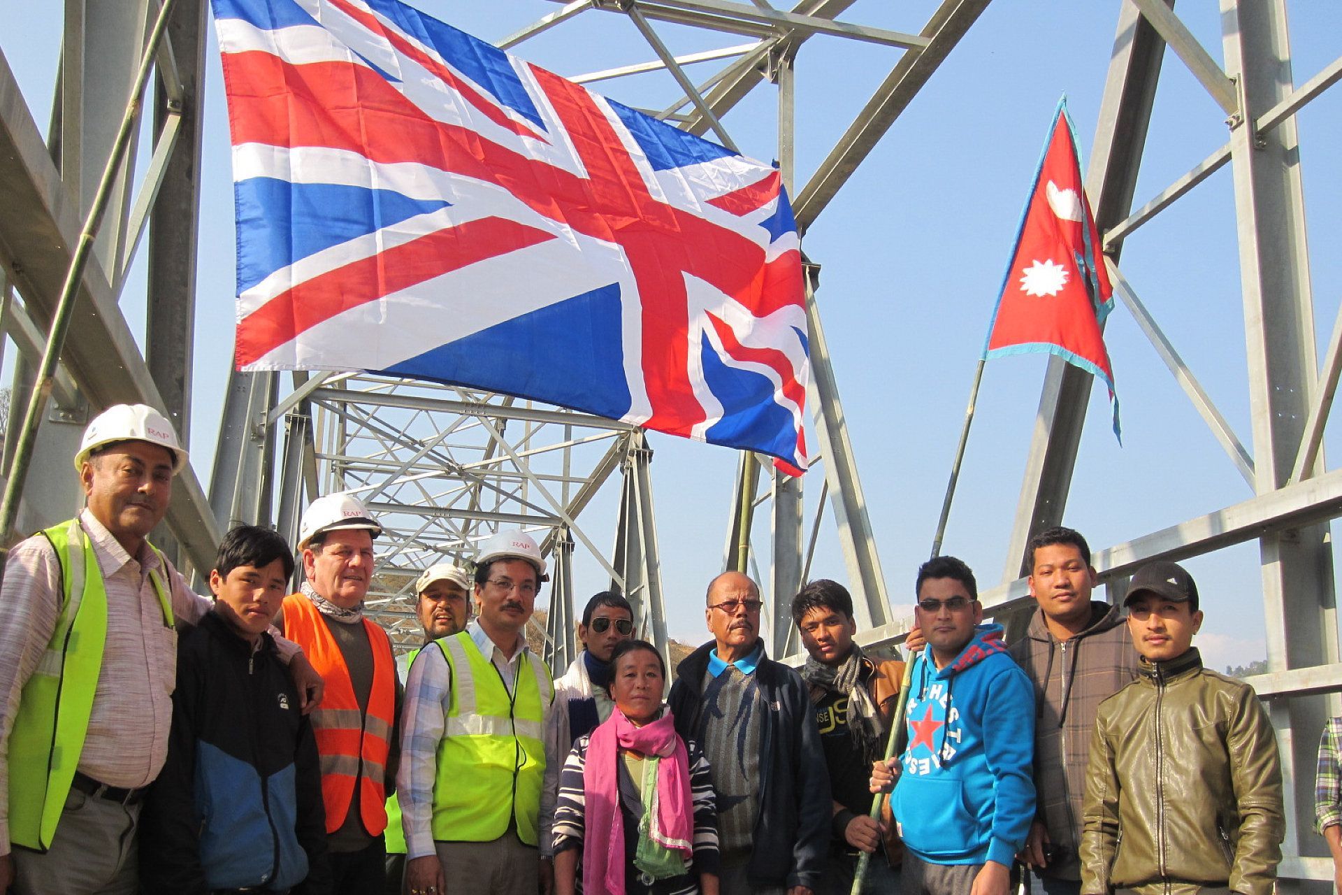 A group of people standing in front of a british flag and a nepal flag