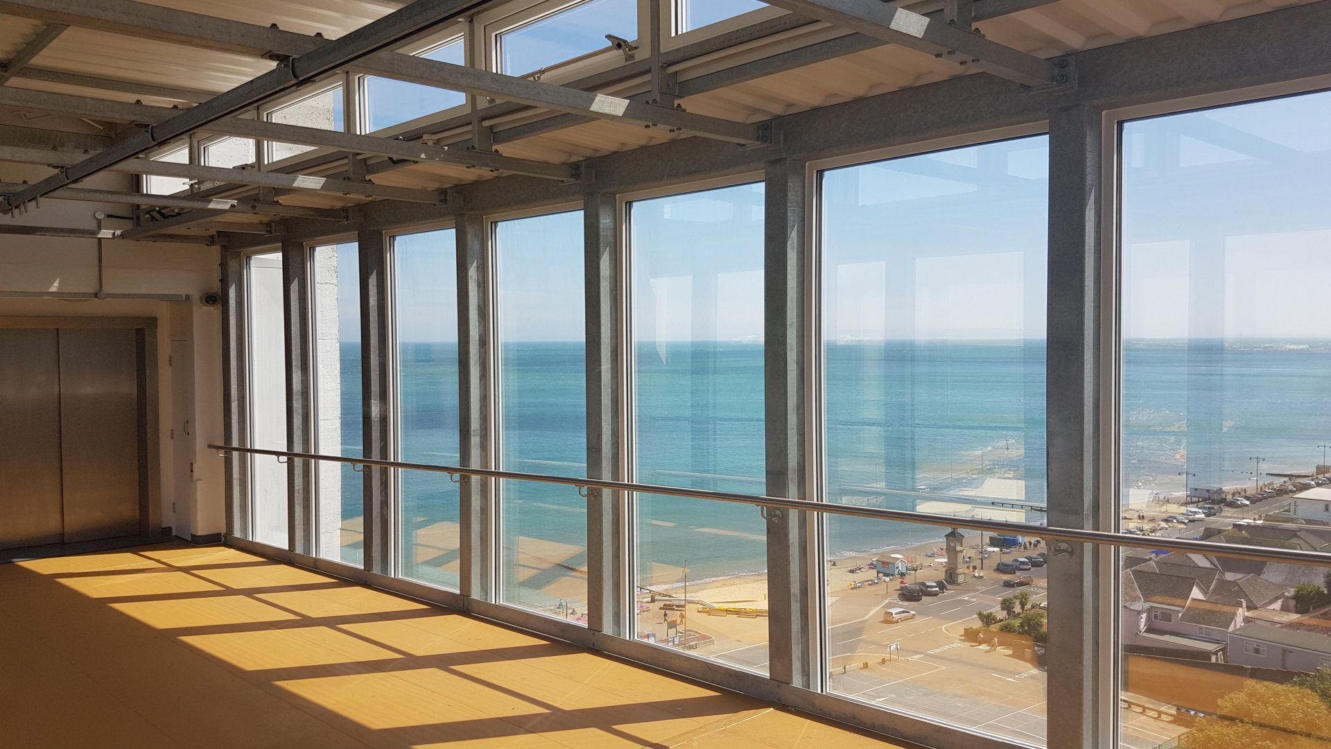 A large room with lots of windows overlooking the ocean.