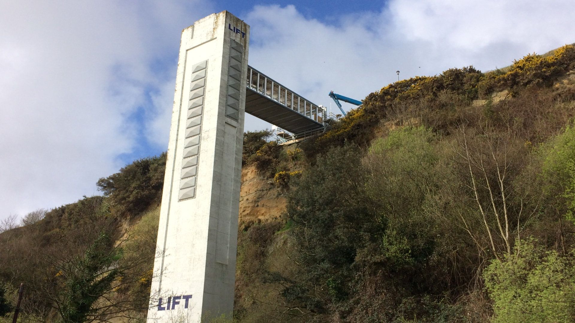 A large concrete tower is sitting on top of a hill surrounded by trees.