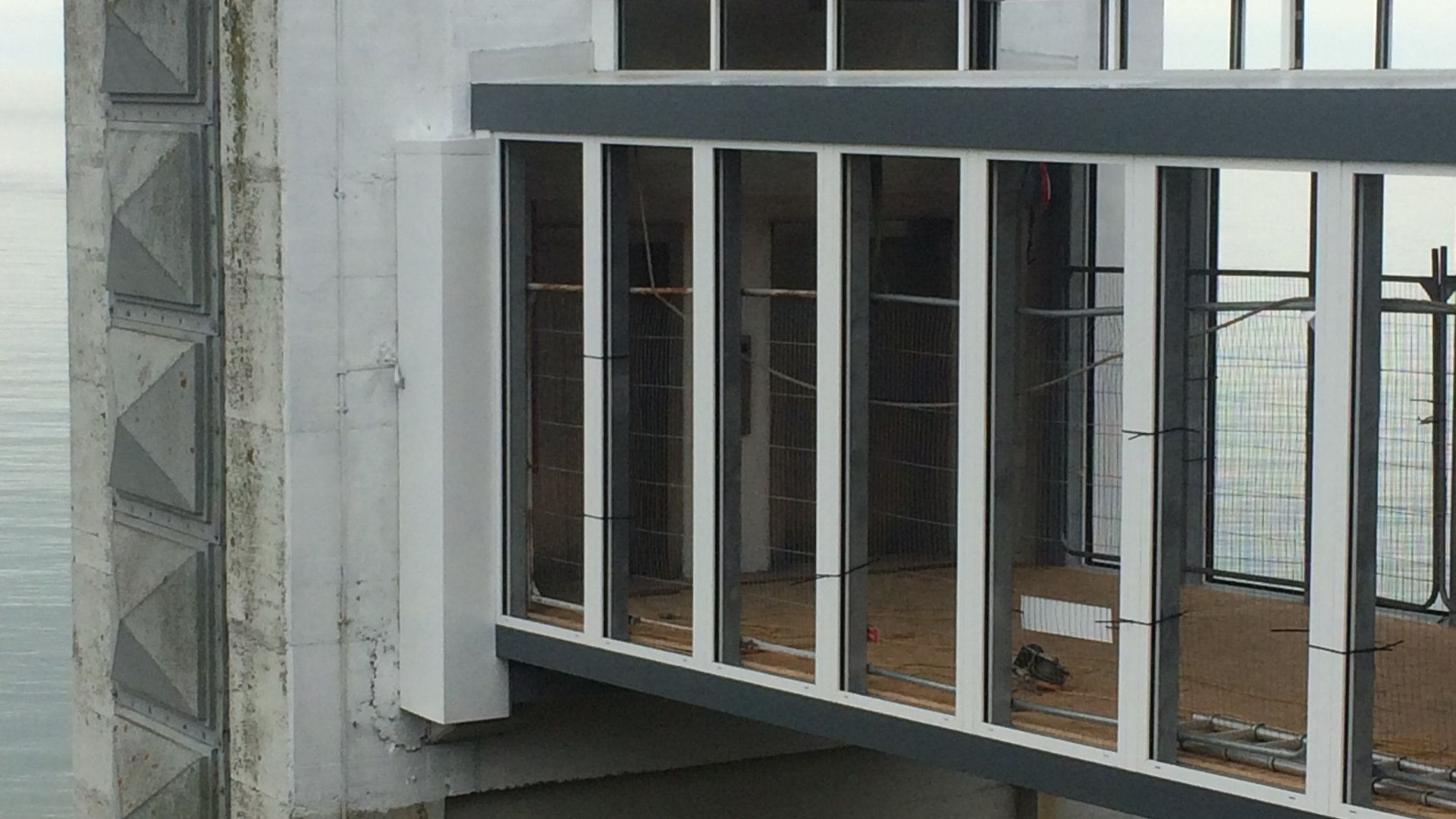 A building under construction with a balcony overlooking the ocean.