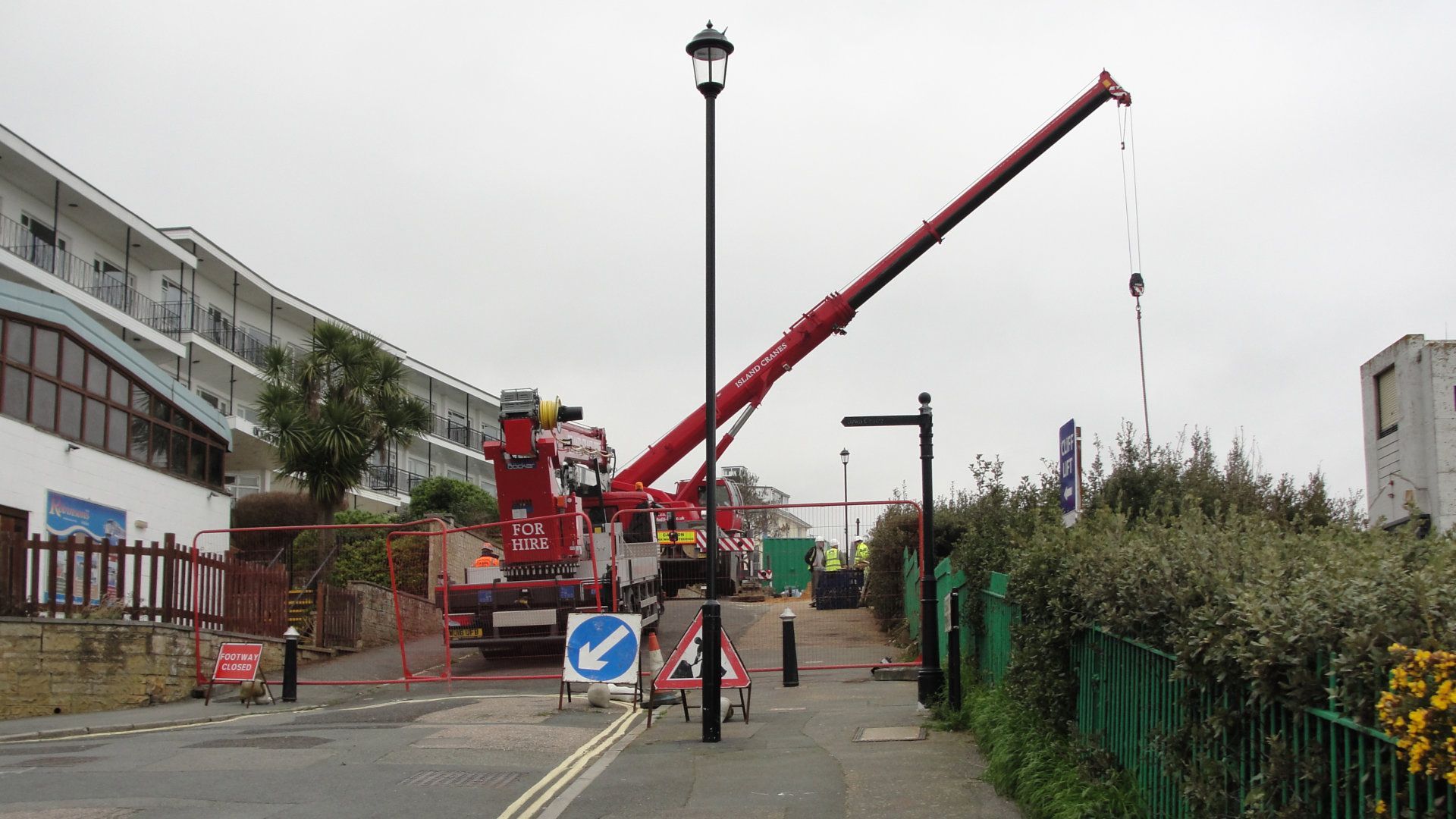 A large red crane is sitting on the side of the road
