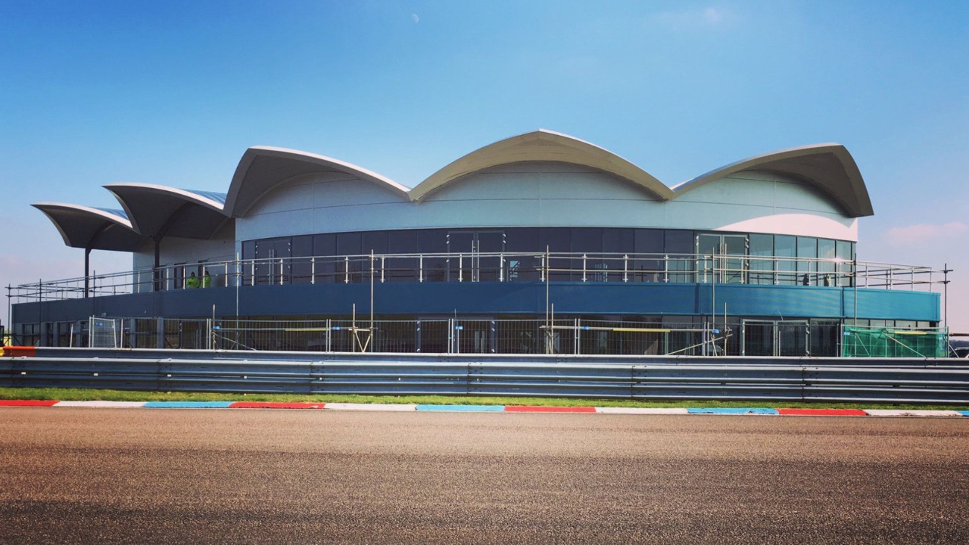 A large building with a curved roof is sitting on top of a race track.
