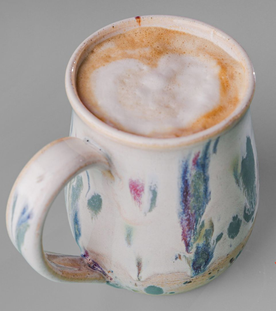 Coffee in a handmade mug, foam art in a heart shape.