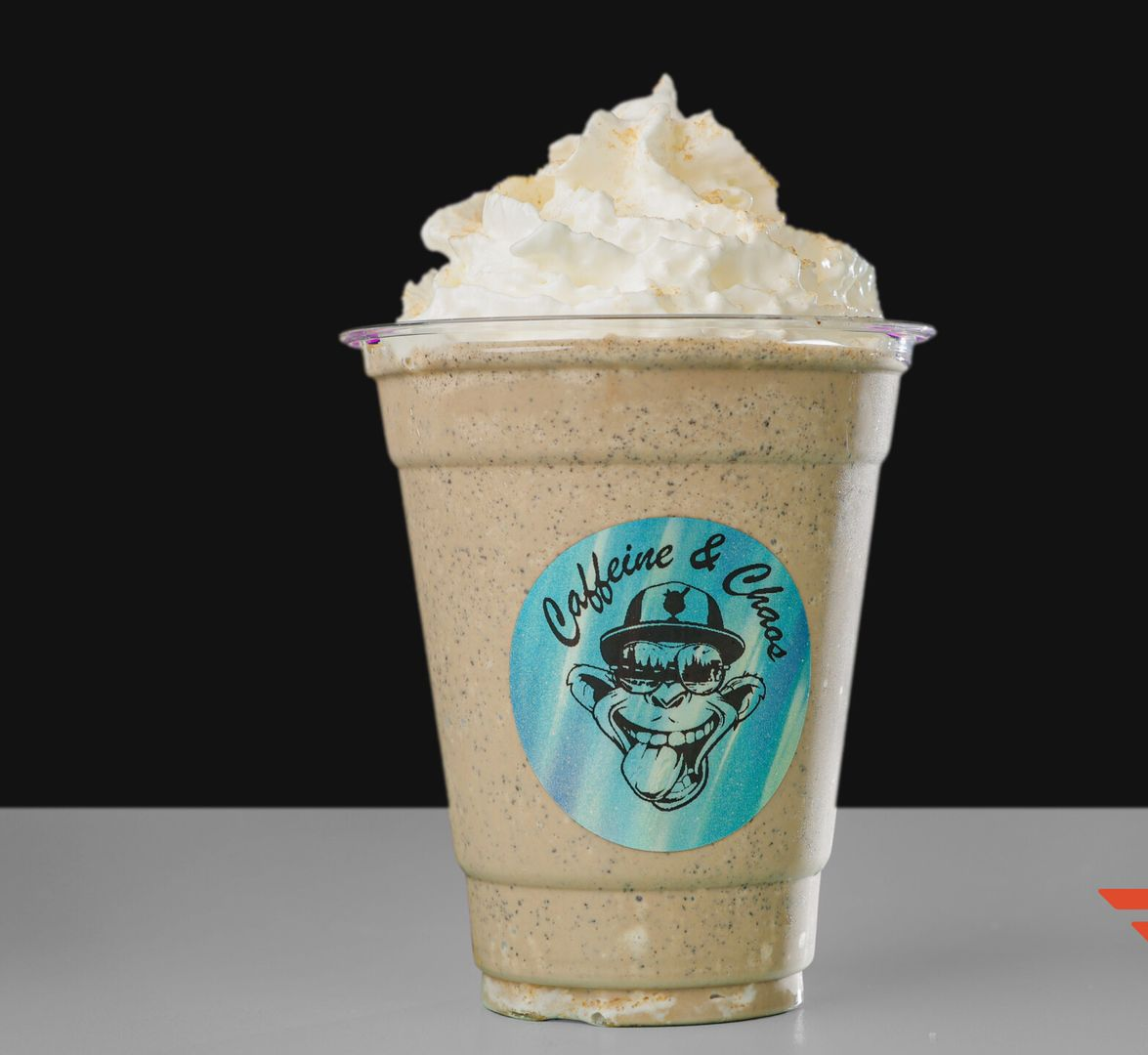 Frappe in a clear cup with whipped cream and a shop logo, on a white surface.