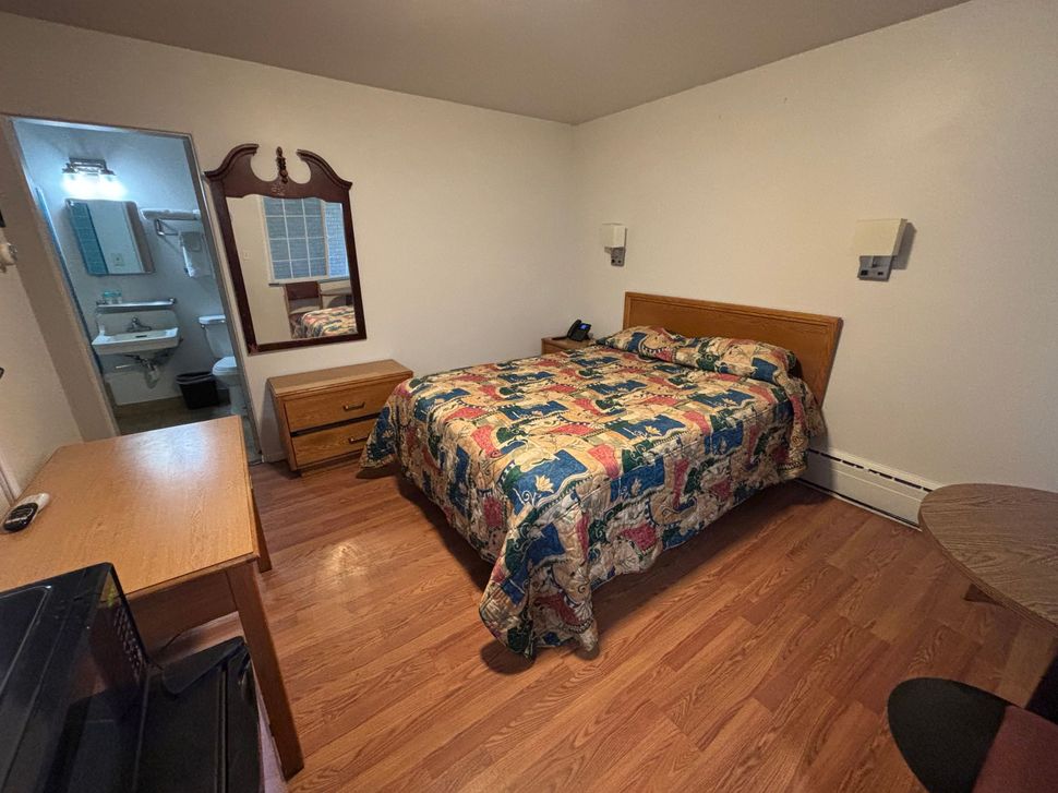 A hotel room with a bed , desk , and mirror.