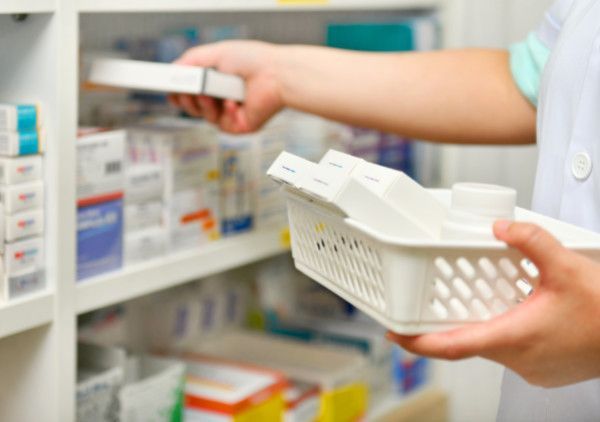 Una persona sostiene una cesta de pastillas en una farmacia.