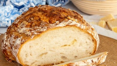 Loaf of crusty bread, one slice cut, on a wooden board.