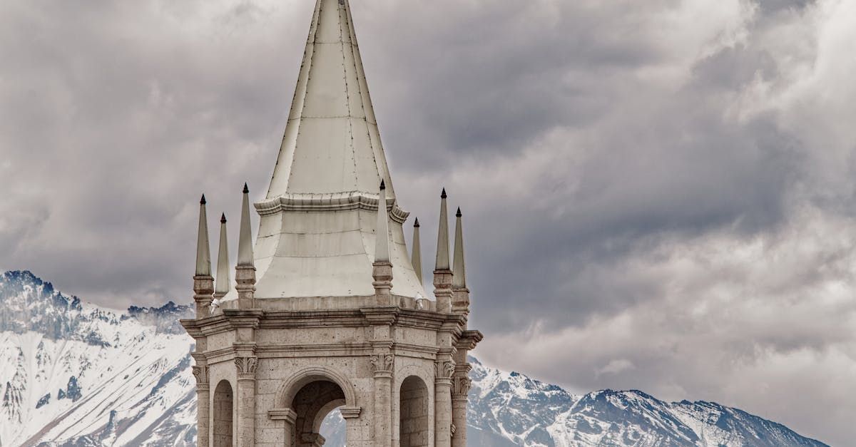 Een hele hoge toren met een besneeuwde berg op de achtergrond.