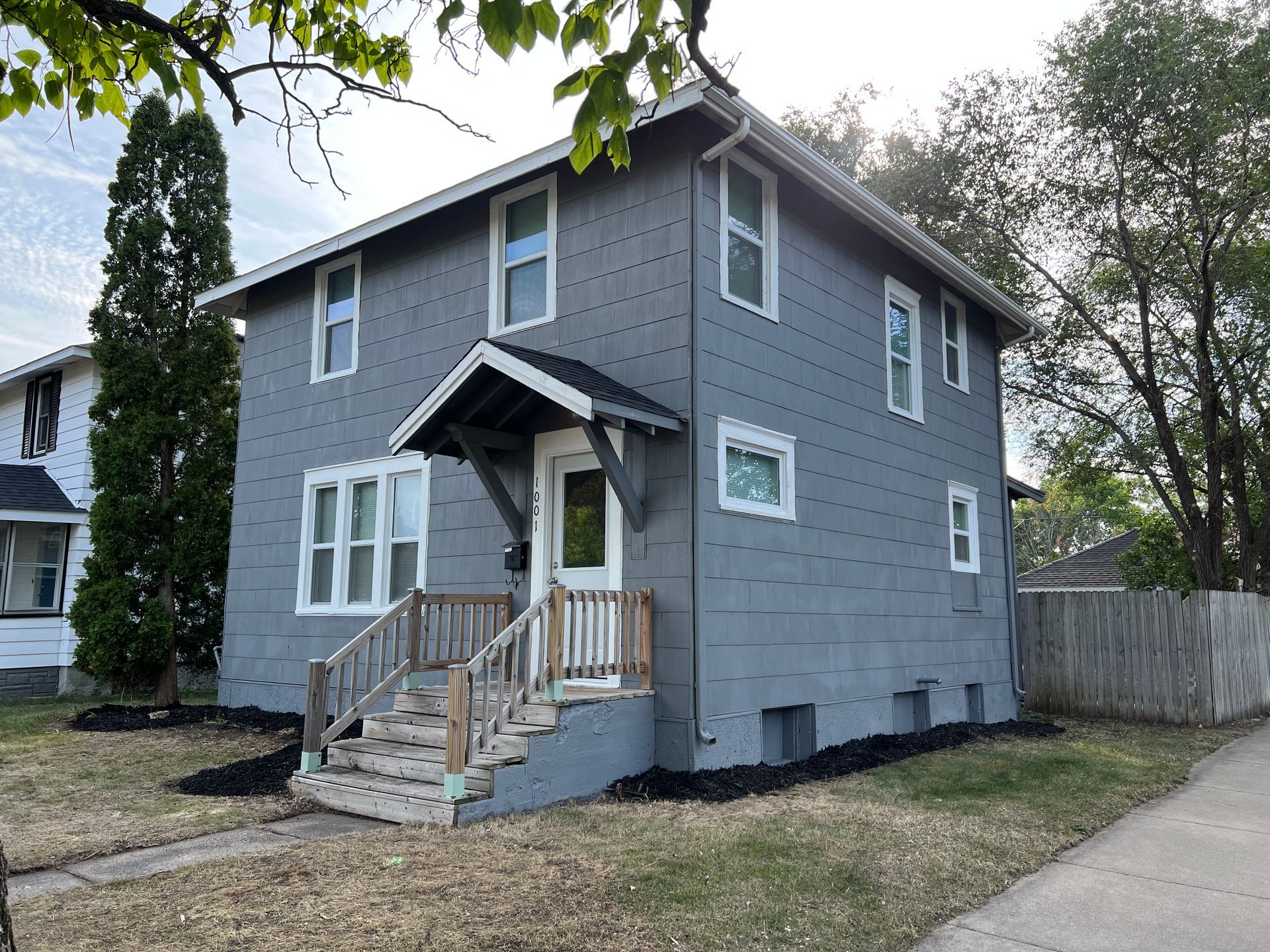 A gray house with stairs leading up to the front door