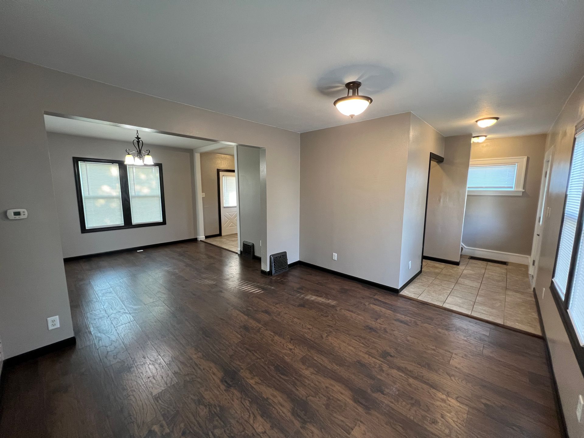An empty living room with hardwood floors and a ceiling fan.