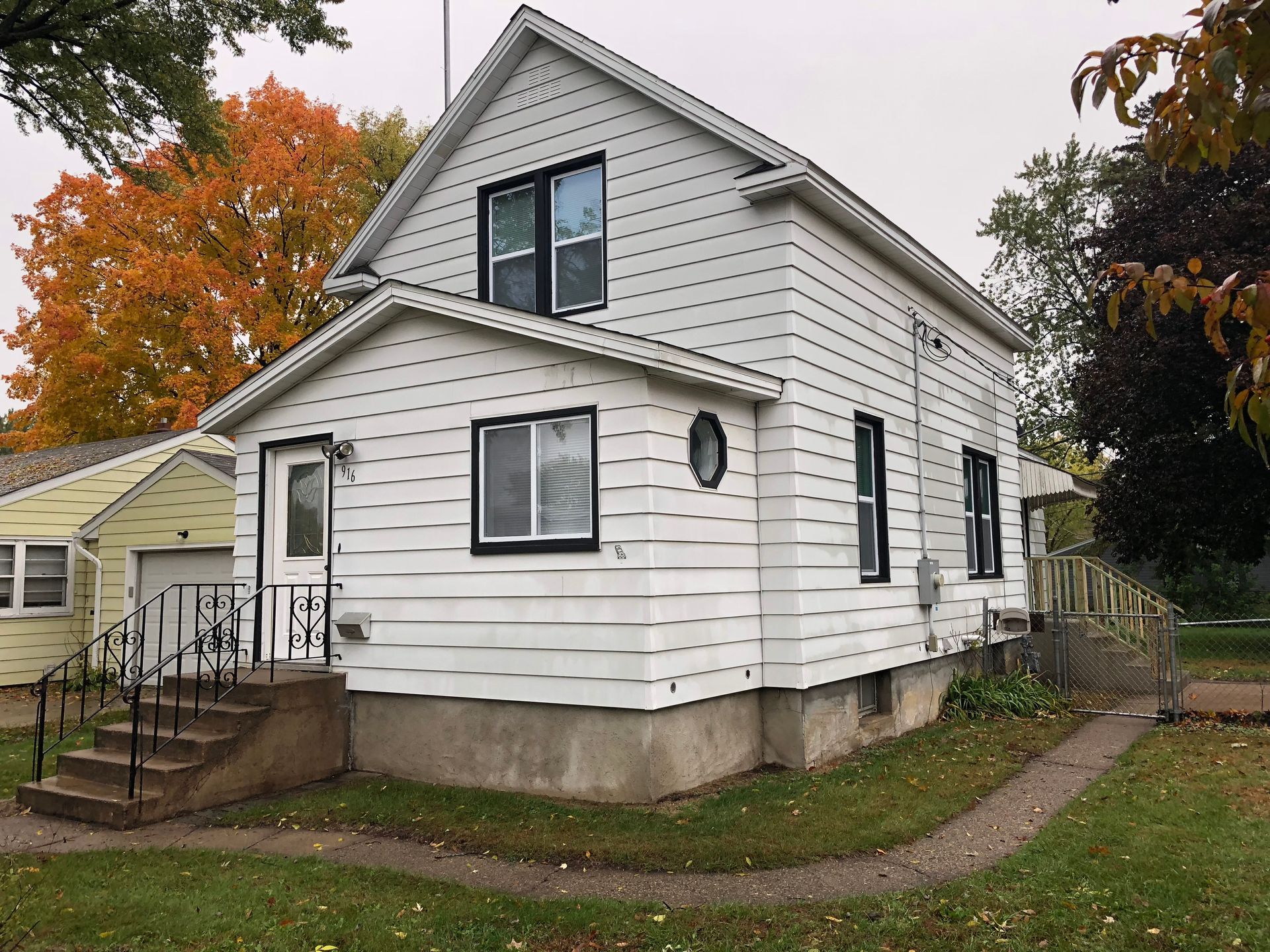 A small white house with stairs leading up to the front door.