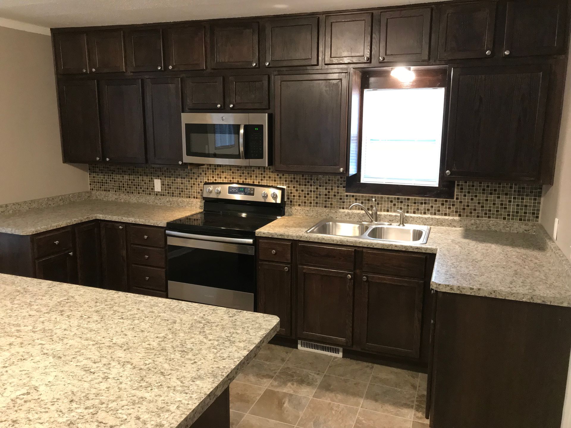 A kitchen with a stove , sink , microwave and cabinets.