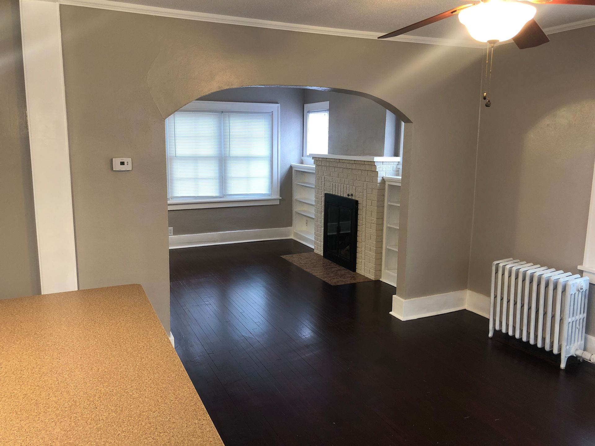 A living room with a fireplace and a ceiling fan