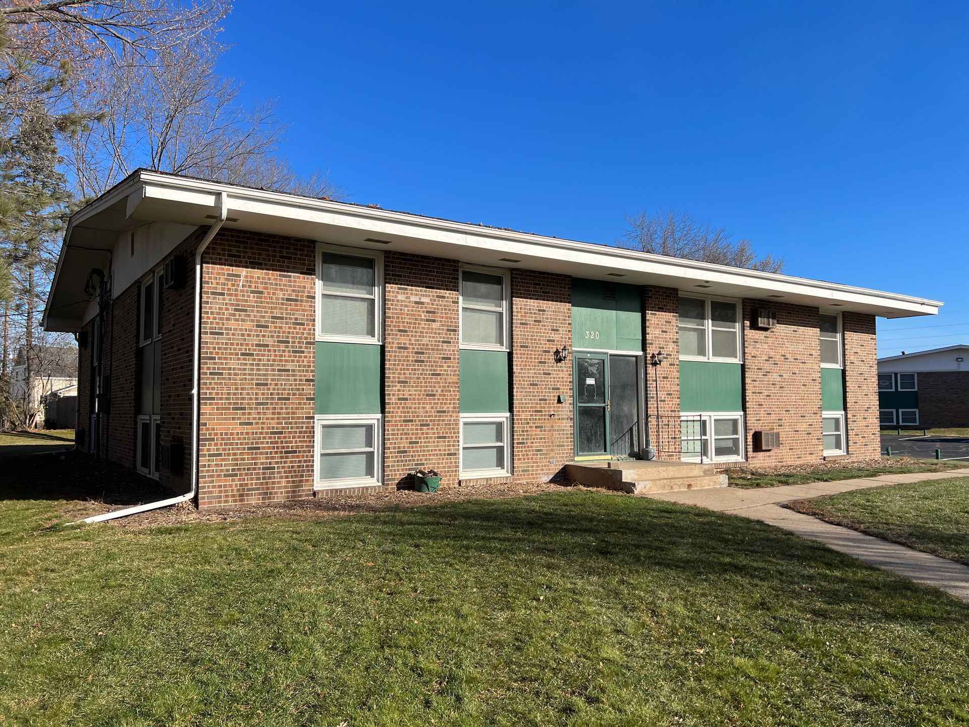 A brick apartment building with green windows and a blue sky in the background.