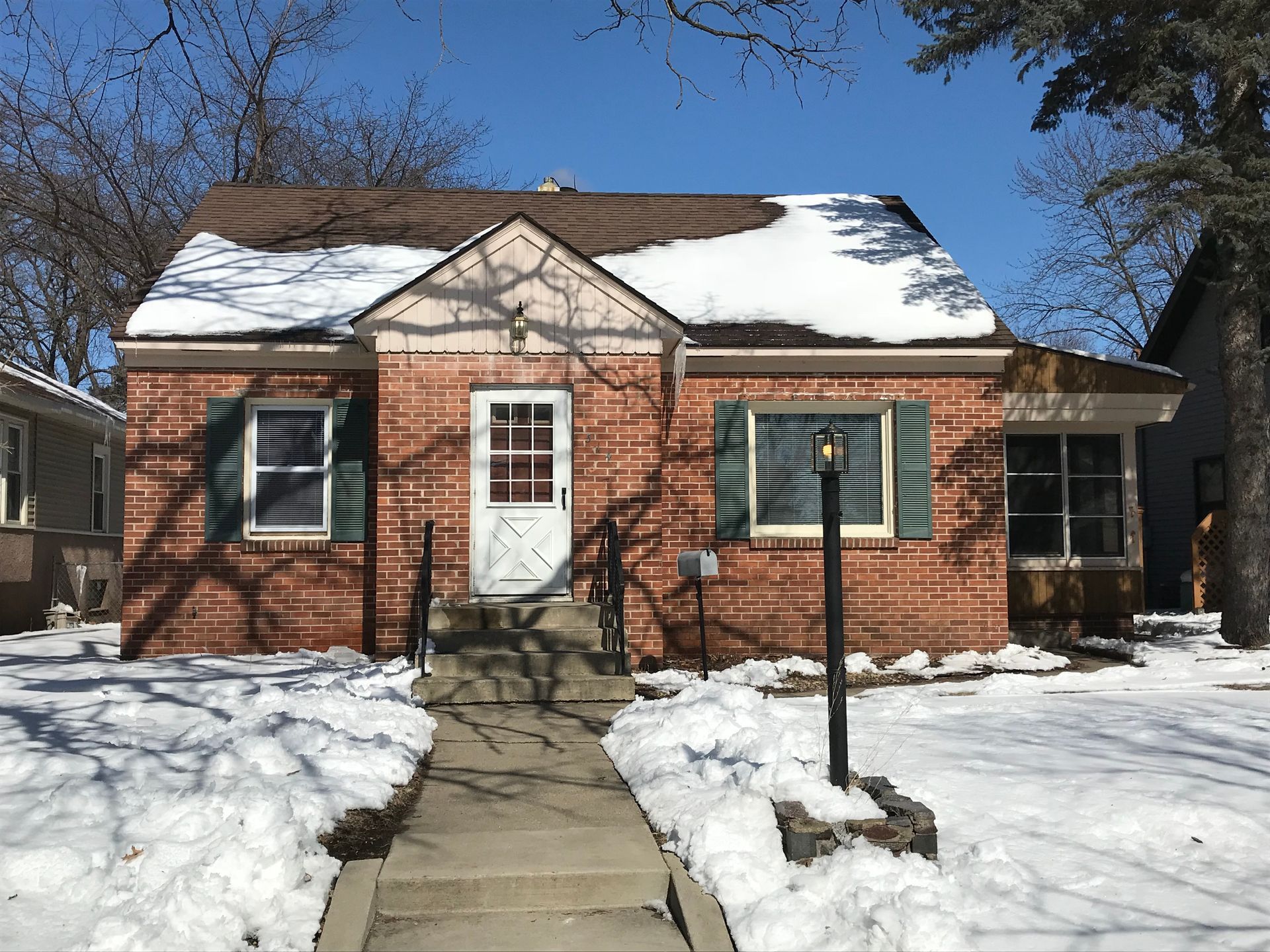 A small brick house with snow on the roof