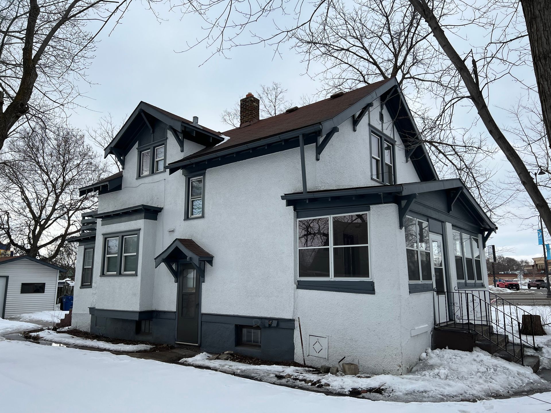 A white house with a brown roof is covered in snow.