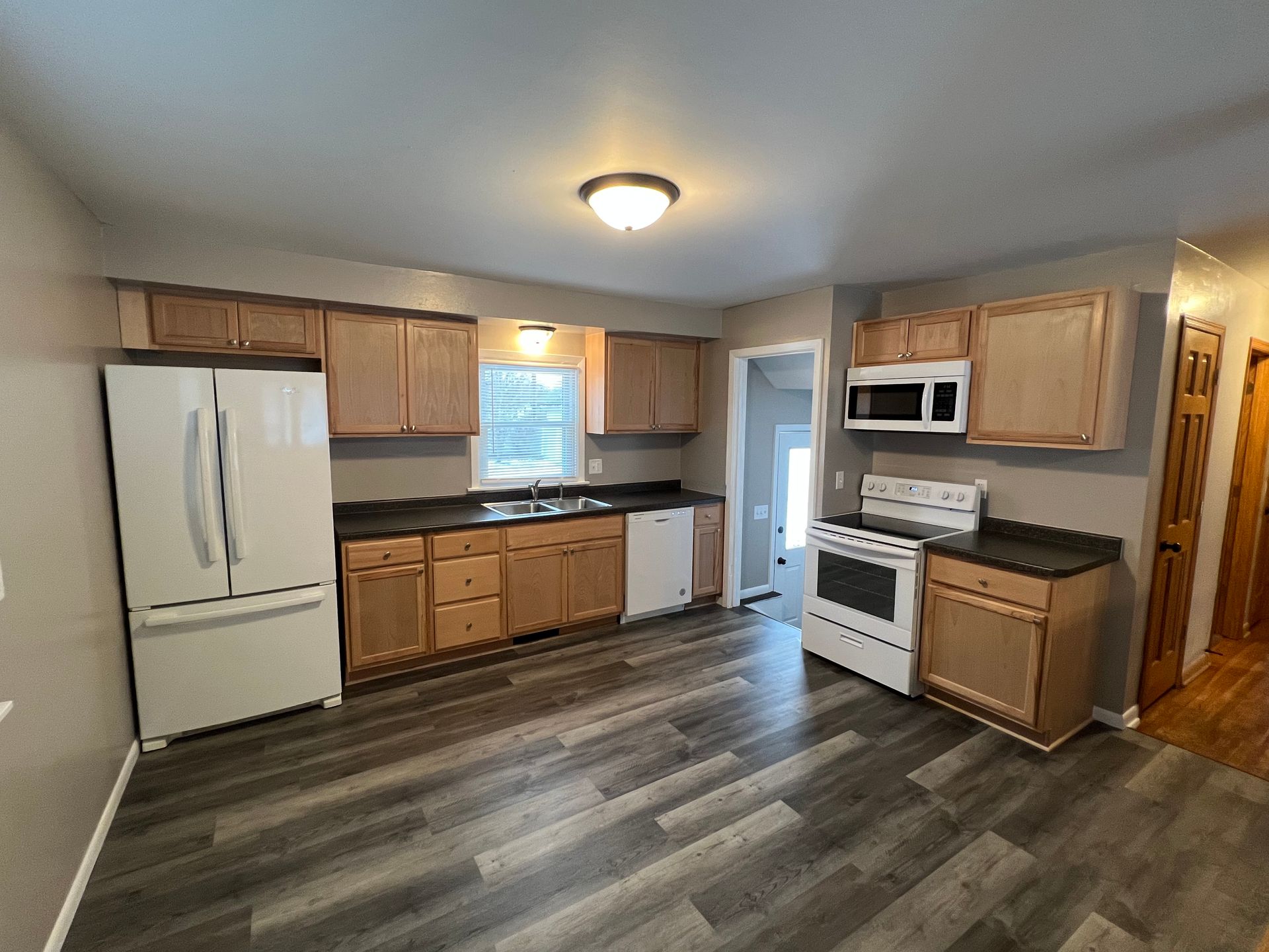 A kitchen with wooden cabinets , a refrigerator , a stove , and a microwave.