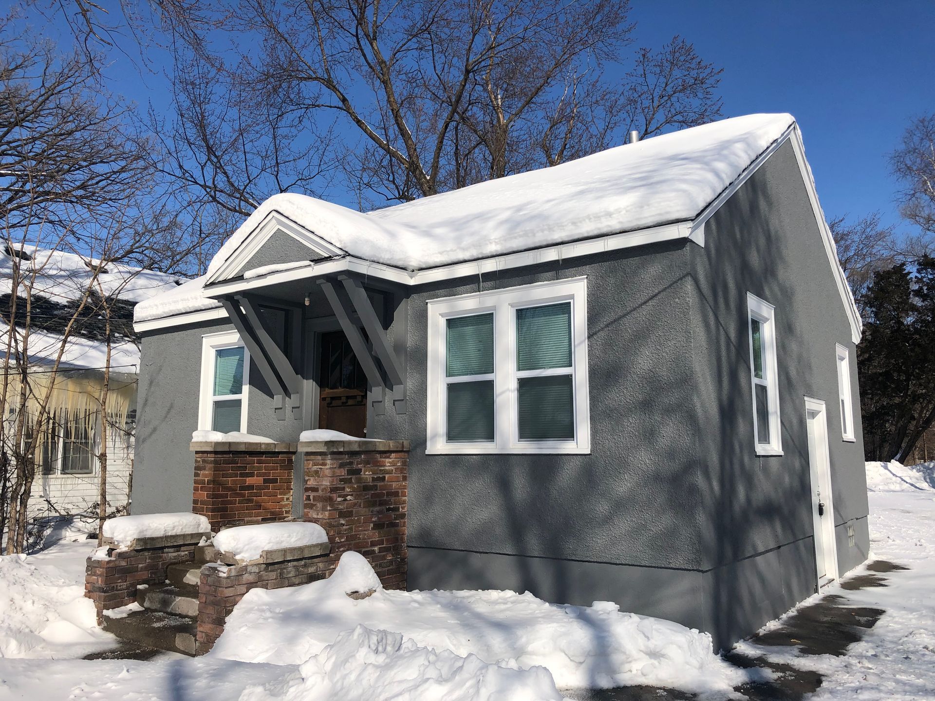 A small house is covered in snow on a sunny day.
