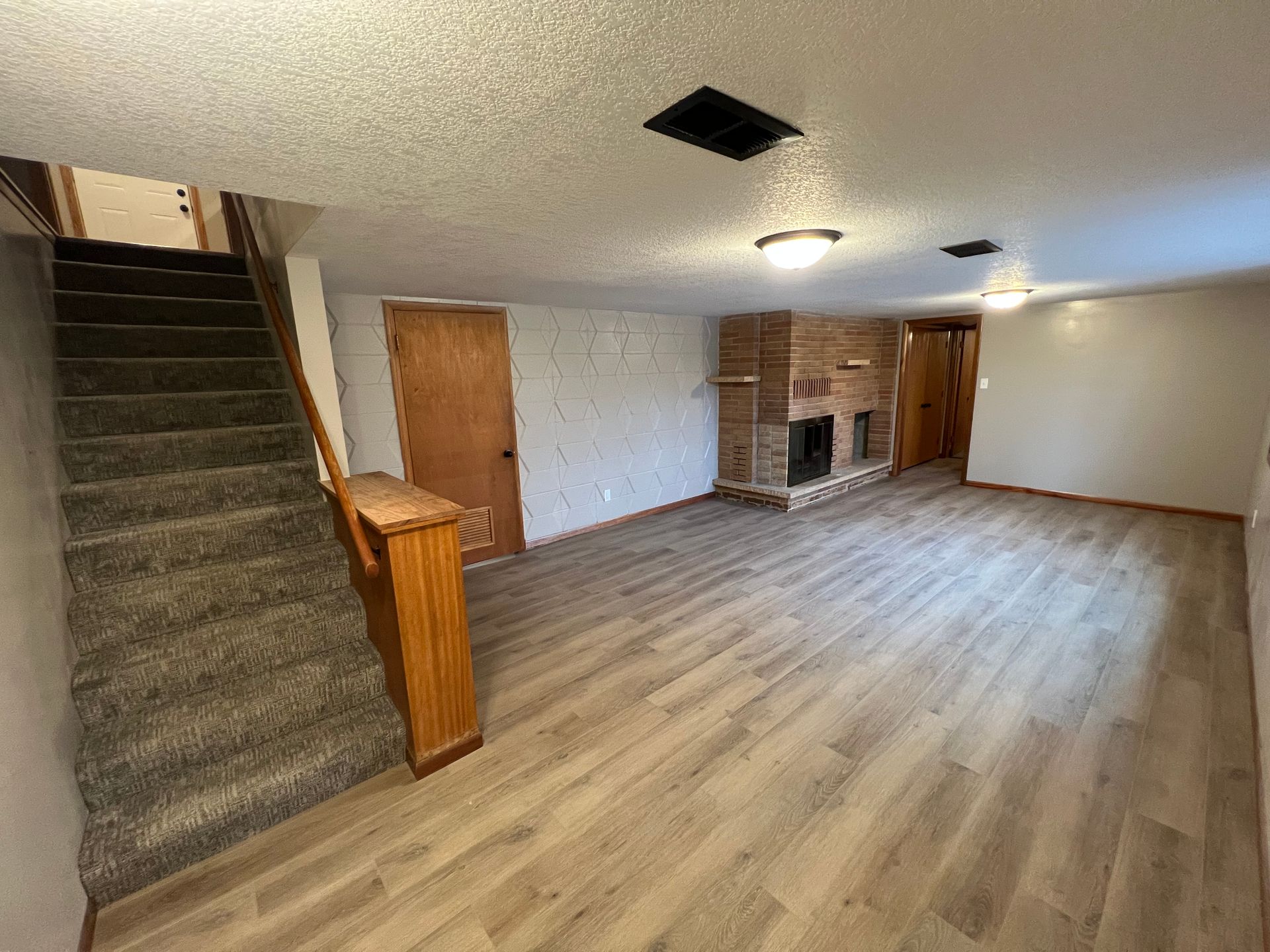 A living room with hardwood floors , stairs and a fireplace.