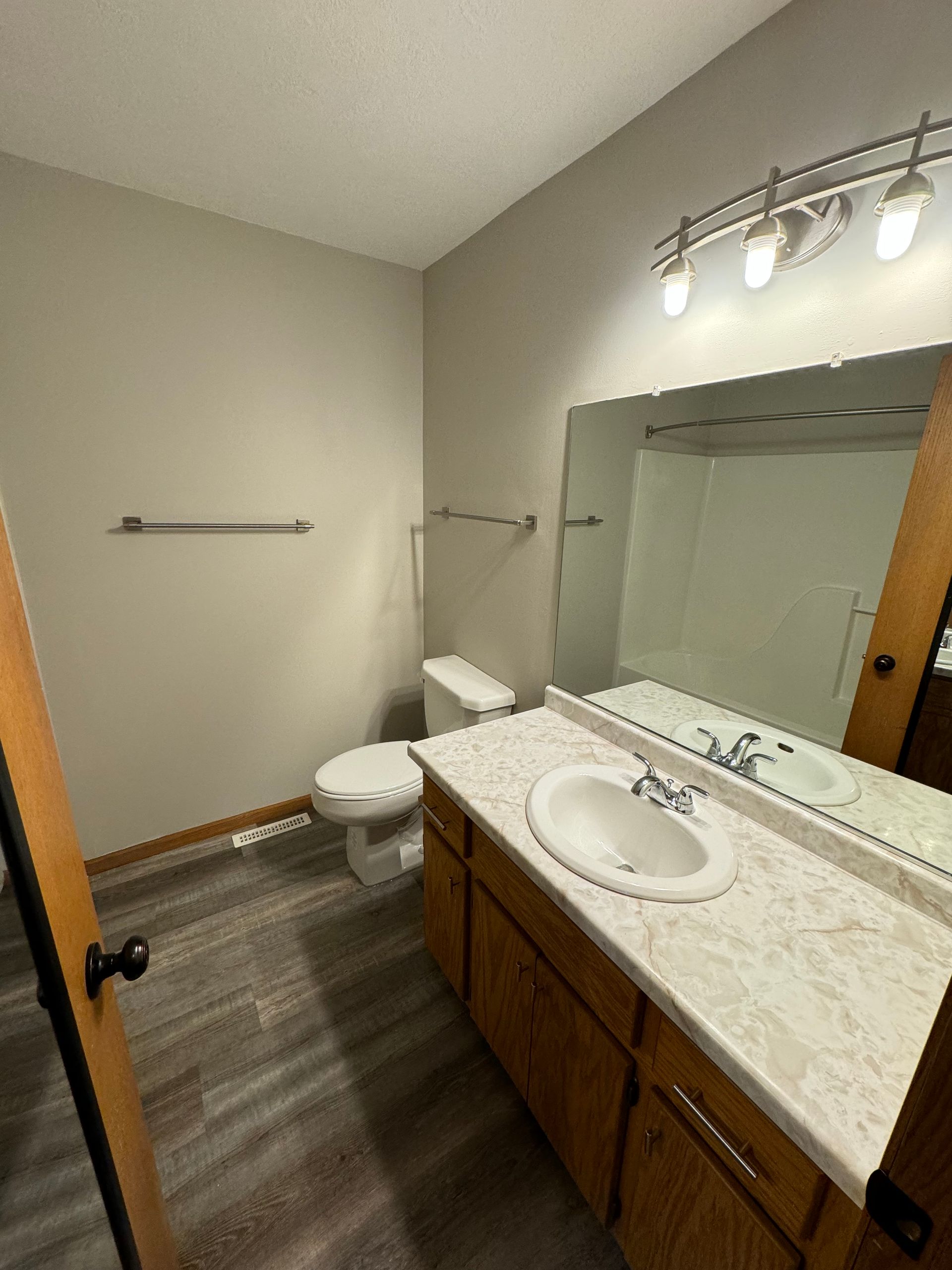 A bathroom with a toilet , sink and mirror.