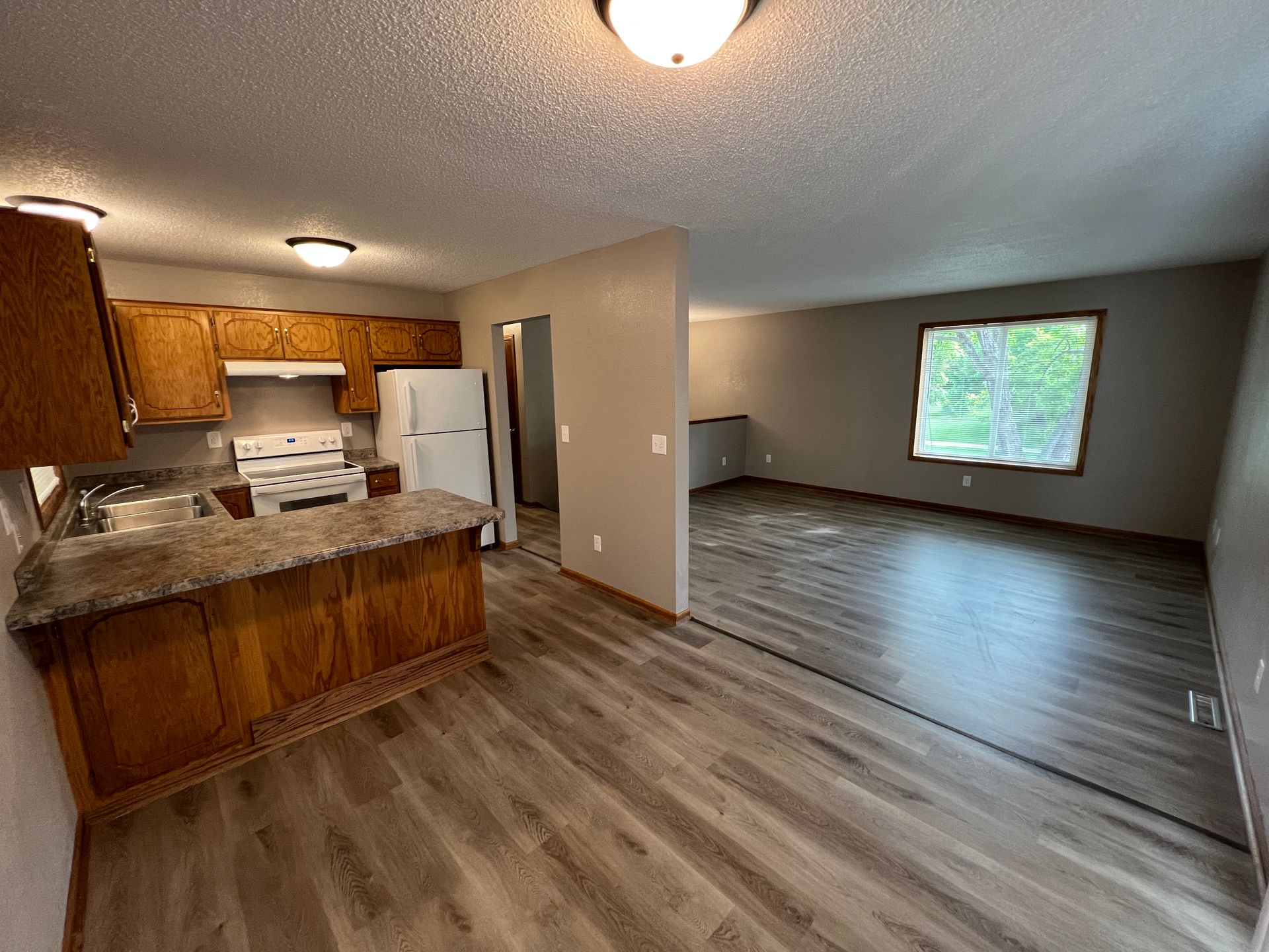 A kitchen and living room in a house with hardwood floors.