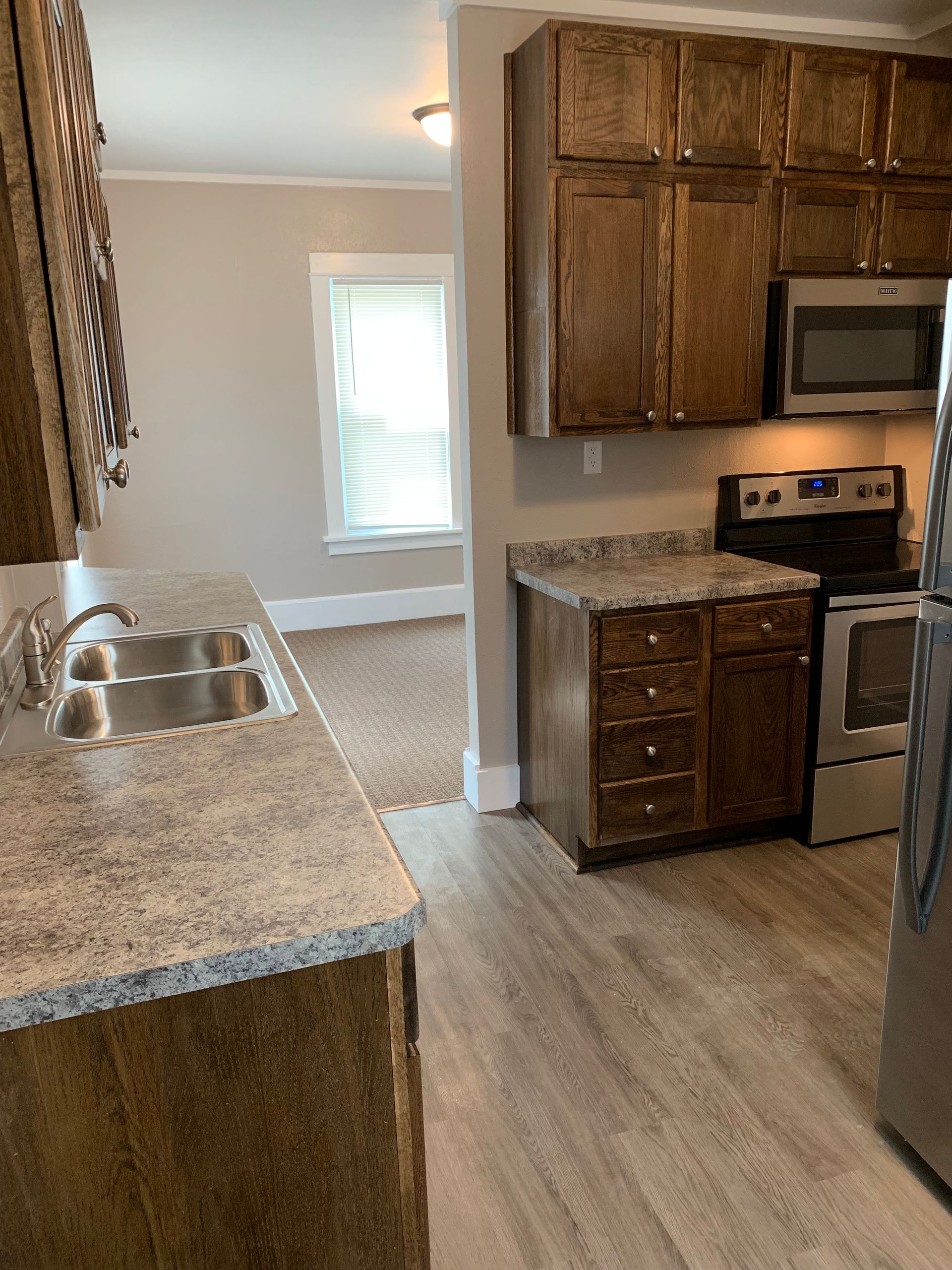 A kitchen with a sink , stove , microwave and refrigerator