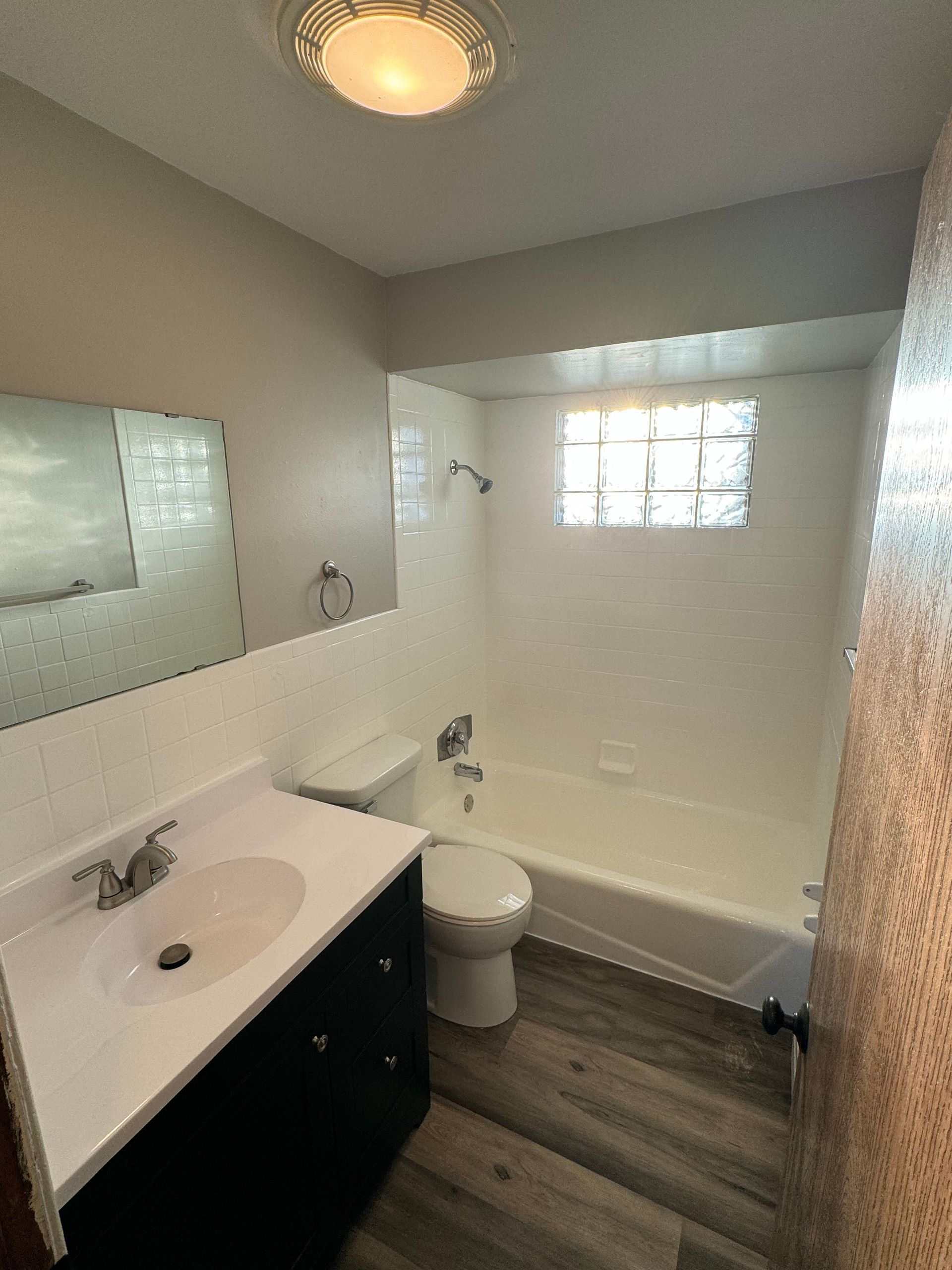 A bathroom with a sink , toilet , tub and mirror.