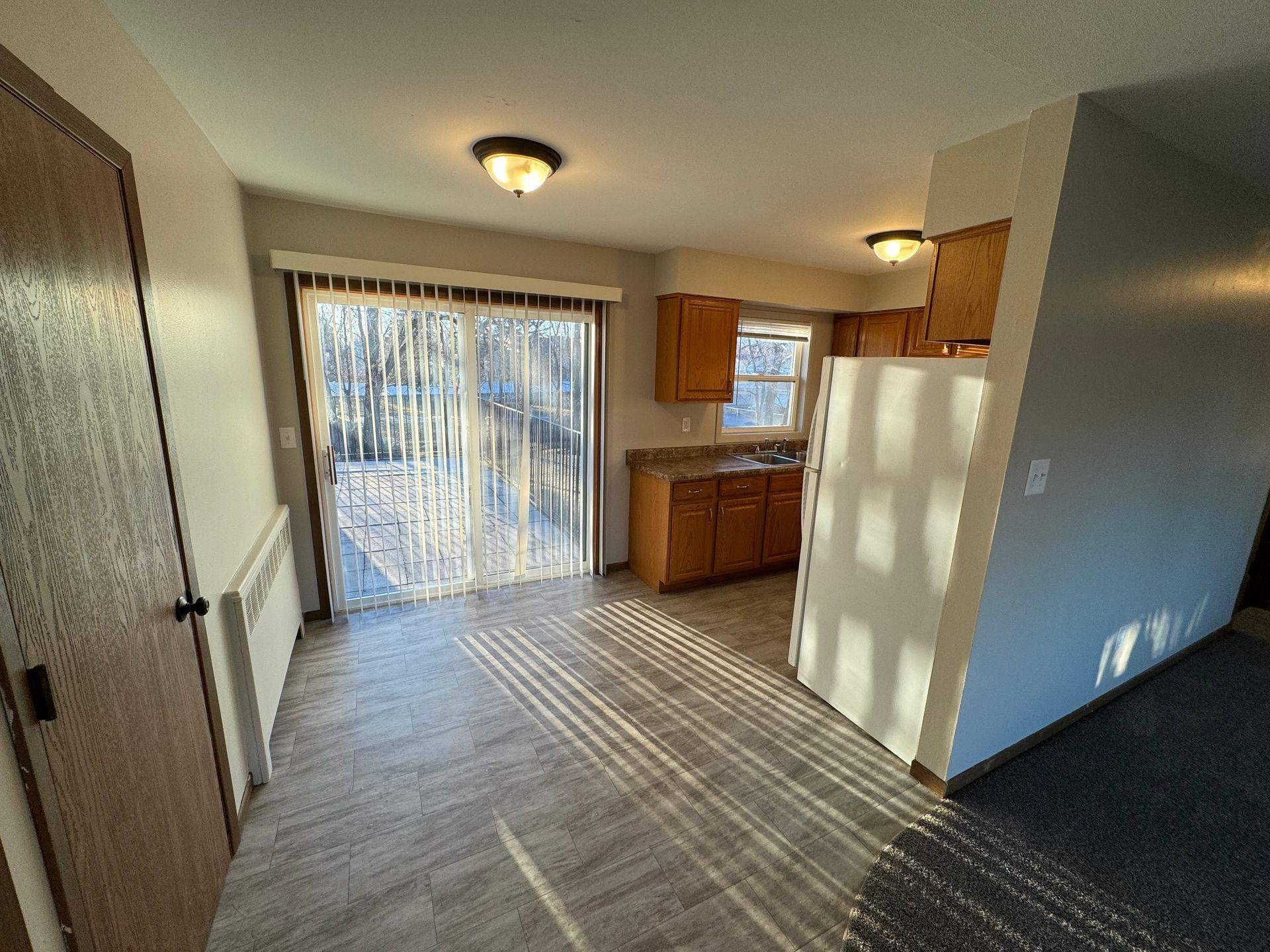 A living room with a sliding glass door leading to a kitchen.
