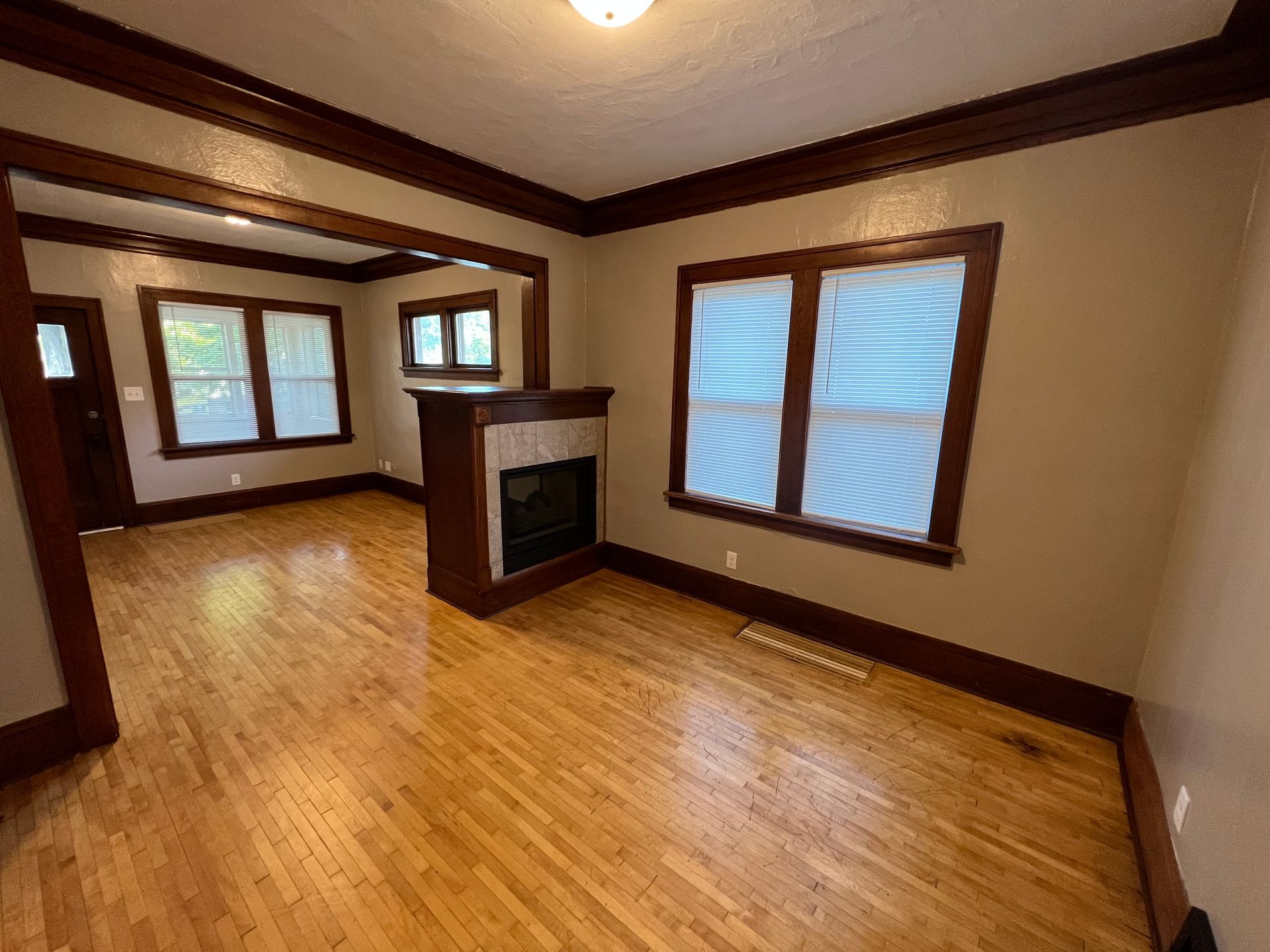 An empty living room with hardwood floors and a fireplace.