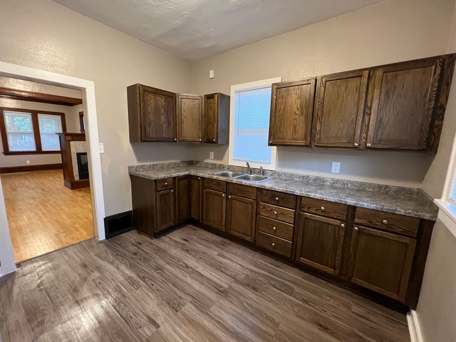 A kitchen with wooden cabinets , granite counter tops , and a sink.