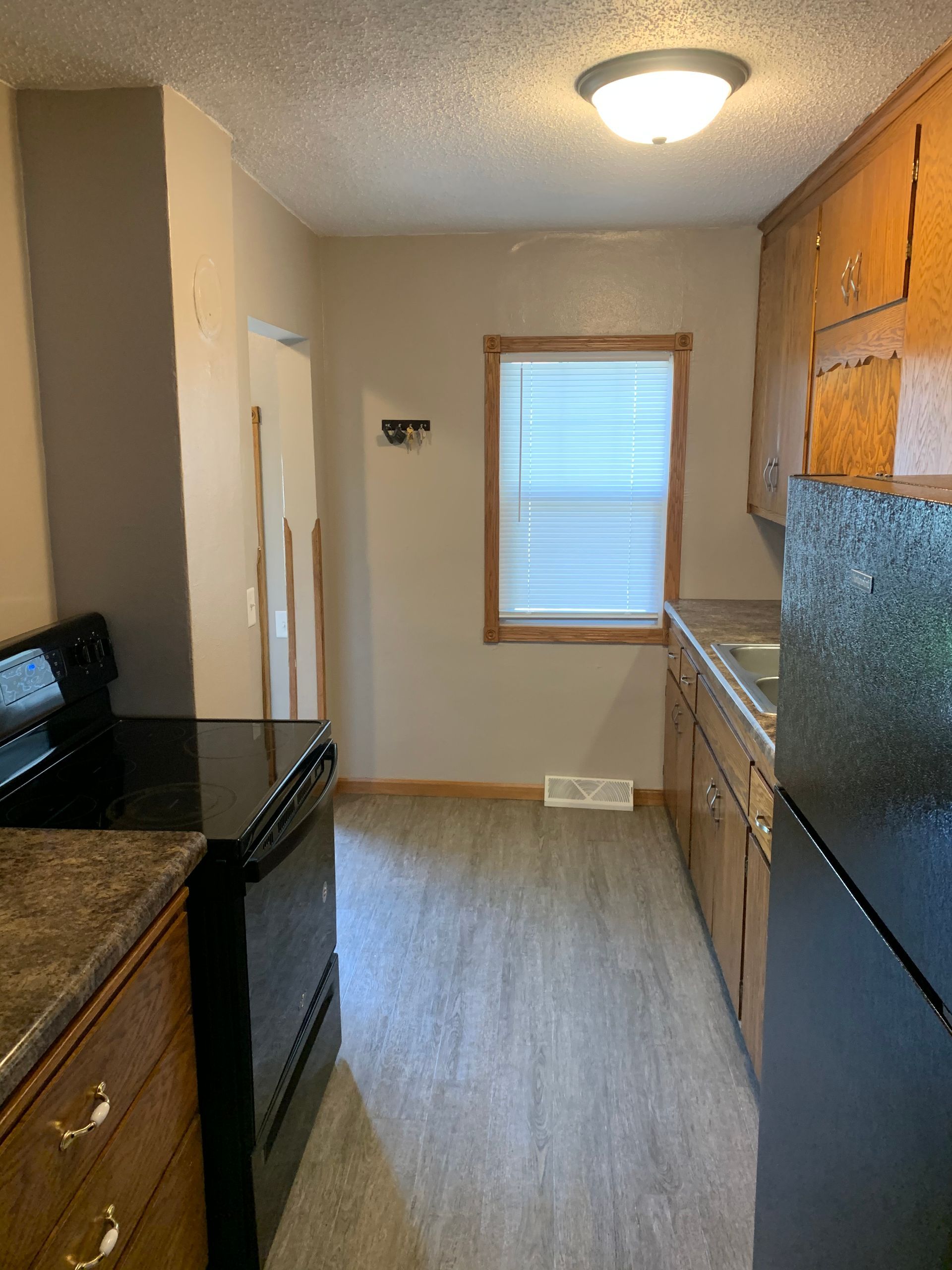 A kitchen with a stove , refrigerator , sink and window.