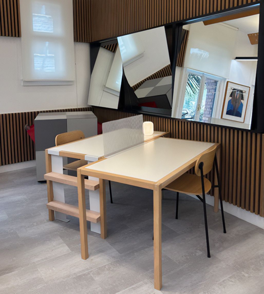 Oficina en casa moderna con escritorio de madera clara, sillas, pared a rayas y espejos apoyados que reflejan la habitación.