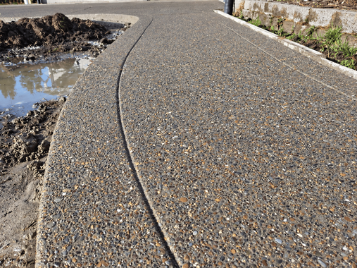 Exposed aggregate concrete walkway with a curved saw-cut line