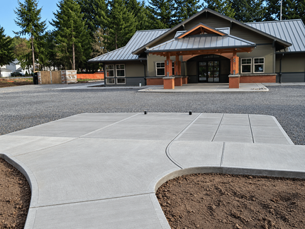 Newly poured concrete slab and sidewalk with forms in place in front of a building