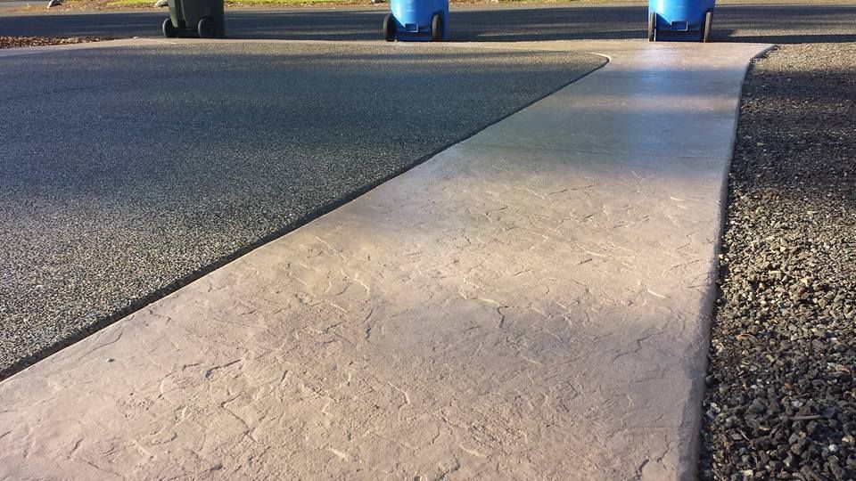 Stained and stamped concrete apron bordering aggregate driveway surface