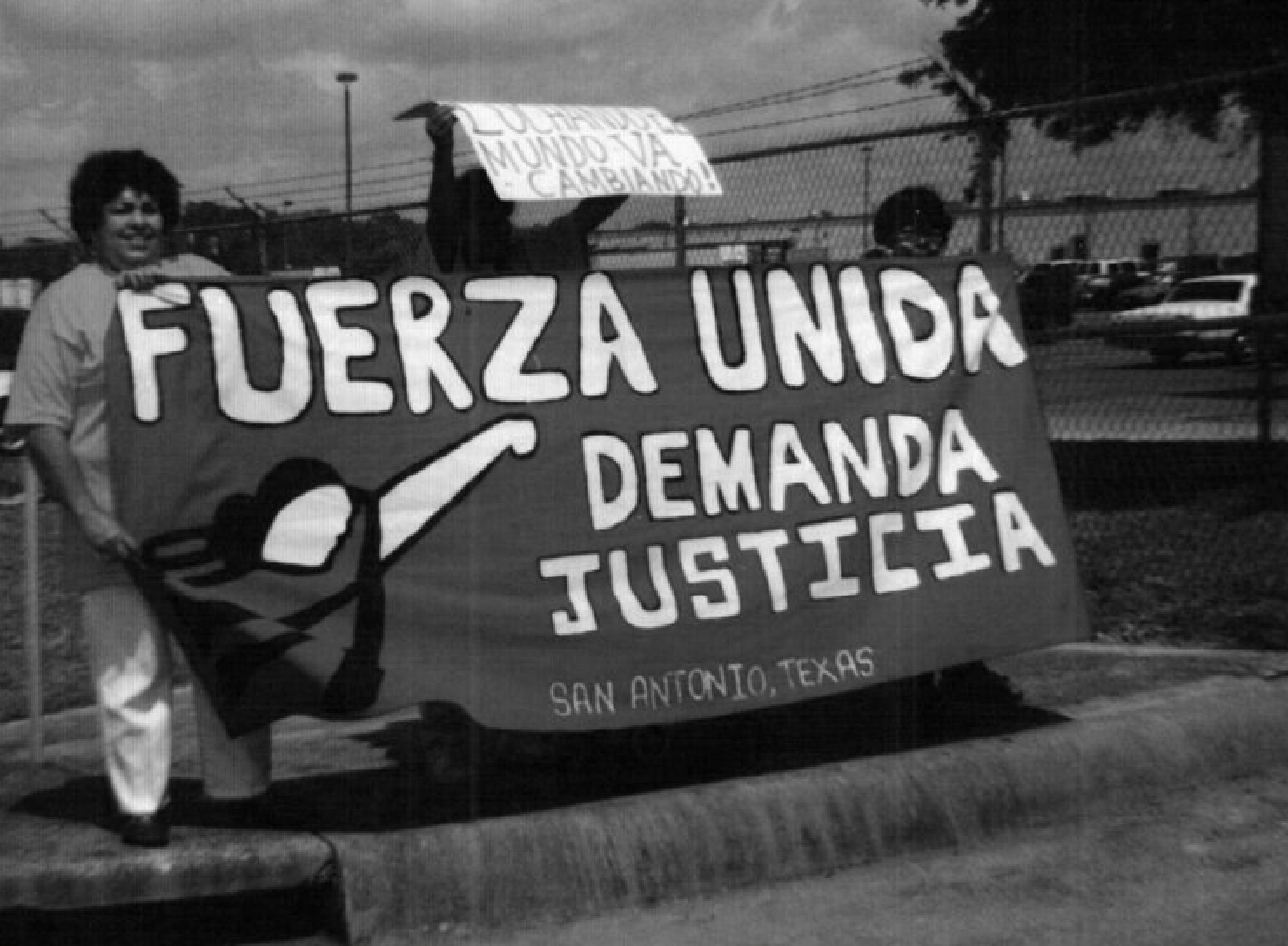 A black and white photo of people holding a sign that says fuerza unida demanda justicia