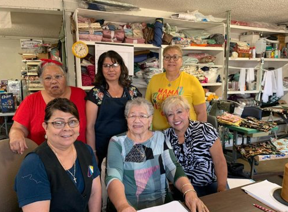 A group of women are posing for a picture in a sewing shop.
