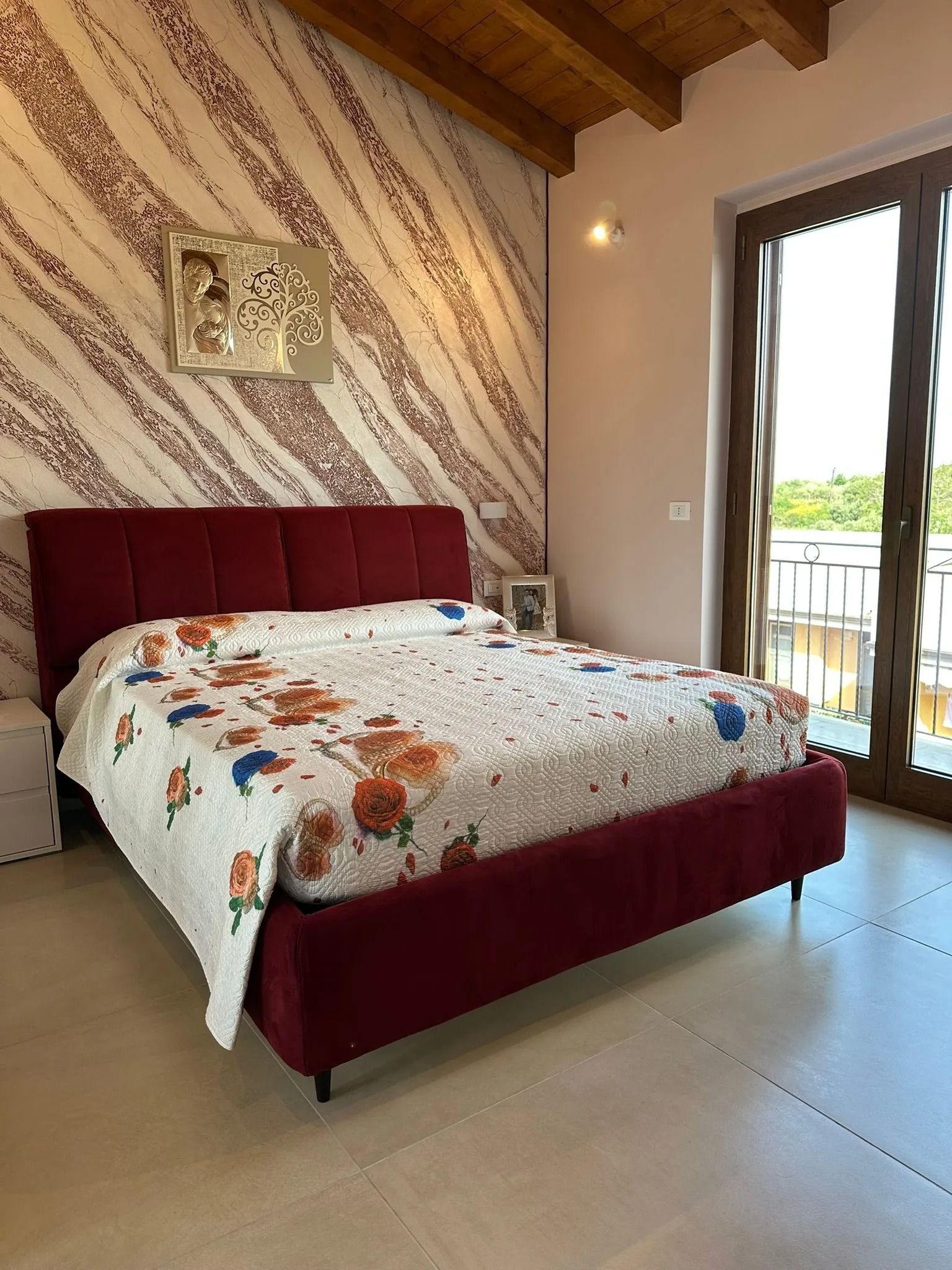 Camera da letto con letto imbottito rosso, trapunta a fiori, soffitto in legno
